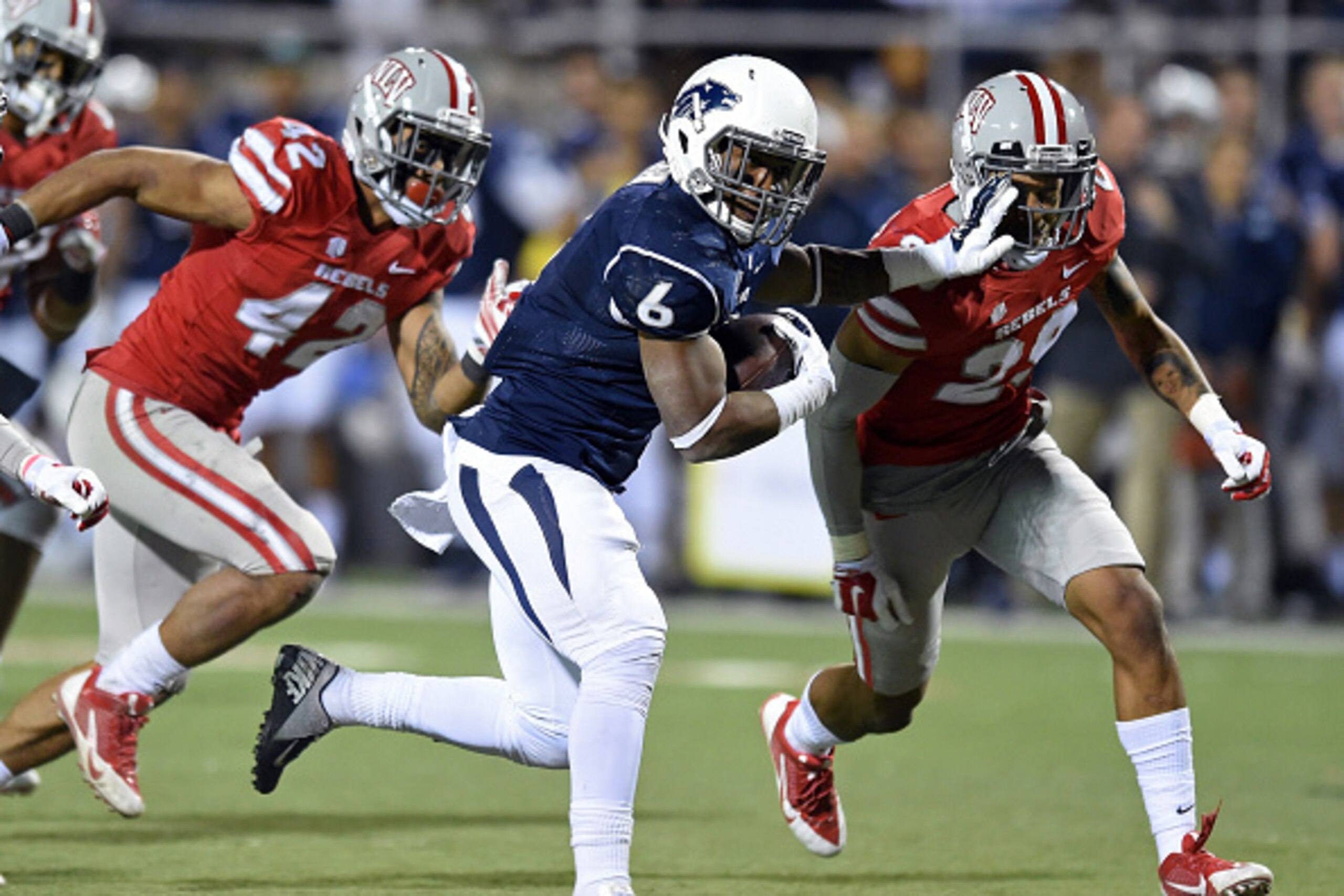 LAS VEGAS, NV - NOVEMBER 29:  Don Jackson #6 of the Nevada Wolf Pack runs for yardage against Peni Vea #42 and Tajh Hasson #29 of the UNLV Rebels during their game at Sam Boyd Stadium on November 29, 2014 in Las Vegas, Nevada. Nevada won 49-27.  (Photo by