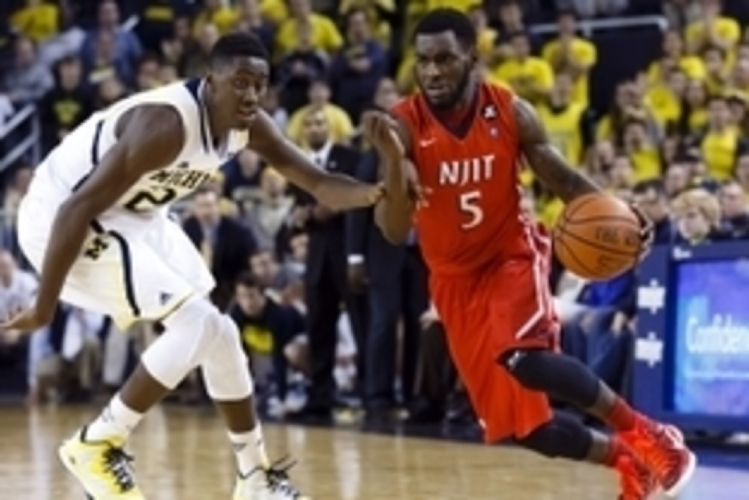 Dec 6, 2014; Ann Arbor, MI, USA; N.J.I.T Highlanders guard Damon Lynn (5) dribbles defended by Michigan Wolverines guard Caris LeVert (23) in the second half at Crisler Center. N.J.I.T won 72-70. Mandatory Credit: Rick Osentoski-USA TODAY Sports
