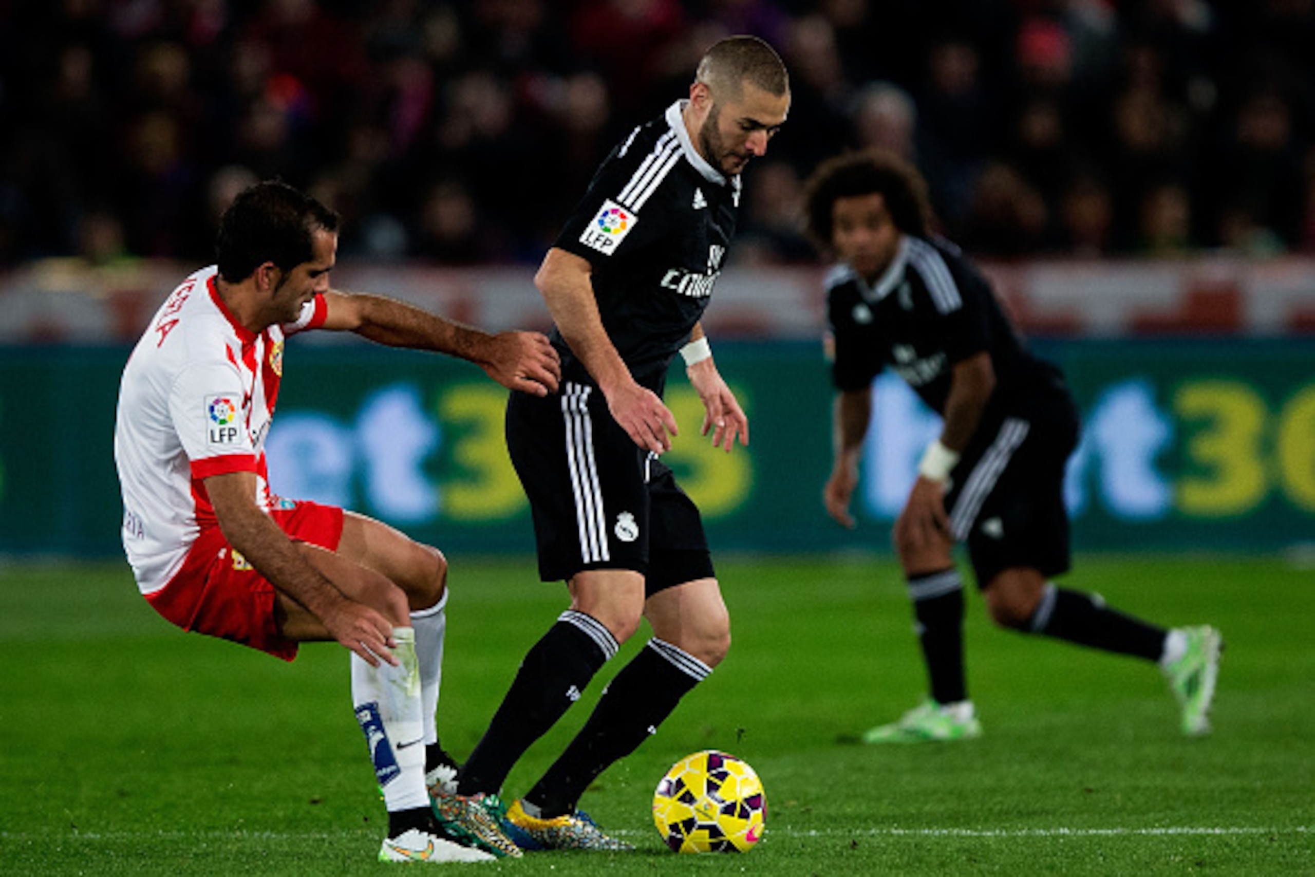 ALMERIA, SPAIN - DECEMBER 12: Karim Benzema (R) of Real Madrid CF competes for the ball with Jose Antonio Garcia Rabasco, alias Verza (L) of Almeria UD during the La Liga match between UD Almeria and Real Madrid CF at Juegos del Mediterraneo stadium on De