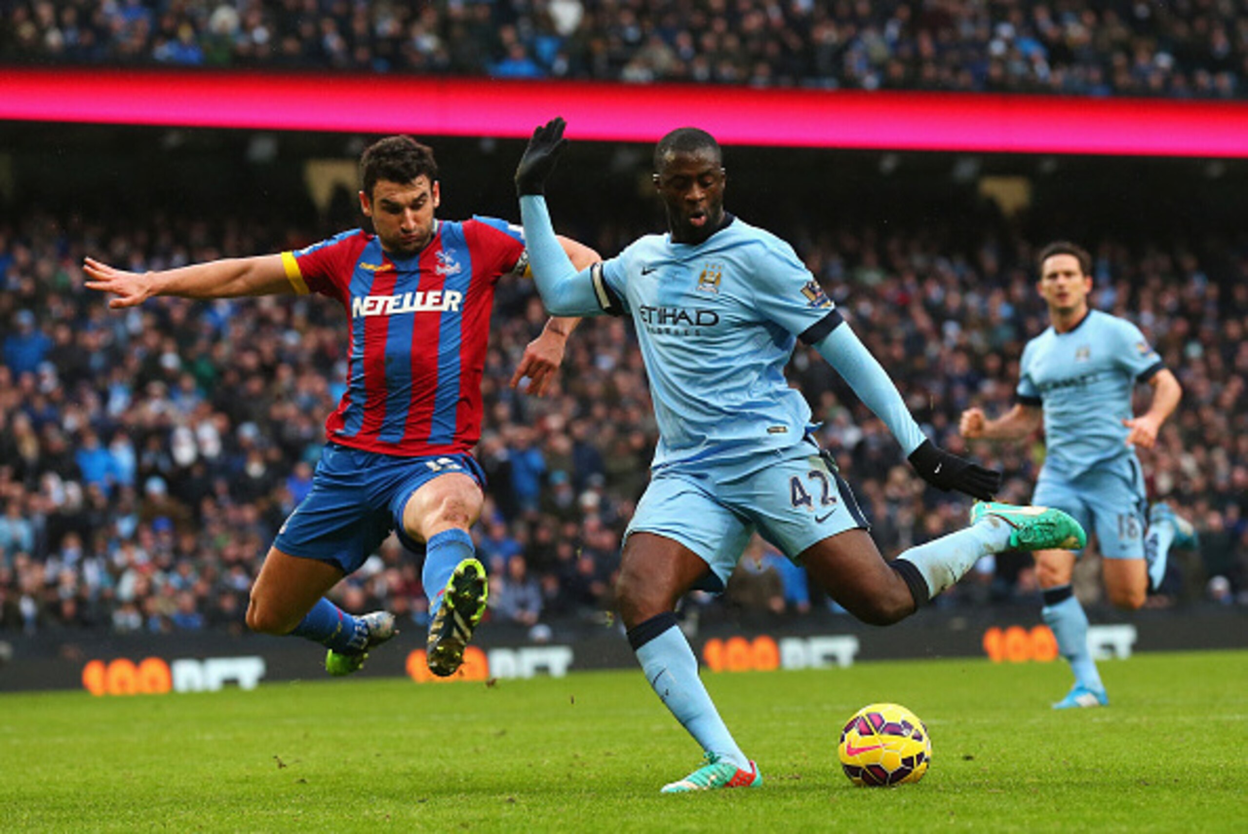 MANCHESTER, ENGLAND - DECEMBER 20:  Yaya Toure of Manchester City scores his goal challenged by Mile Jedinak of Crystal Palace during the Barclays Premier League match between Manchester City and Crystal Palace at Etihad Stadium on December 20, 2014 in Ma