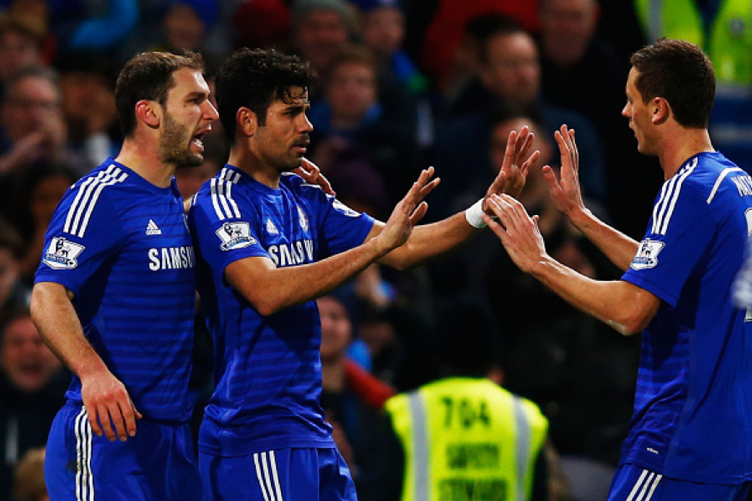 LONDON, ENGLAND - DECEMBER 13:  Diego Costa of Chelsea (C) celebrates with team mates Branislav Ivanovic (L) and Nemanja Matic (R) as he scores their second goal during the Barclays Premier League match between Chelsea and Hull City at Stamford Bridge on 