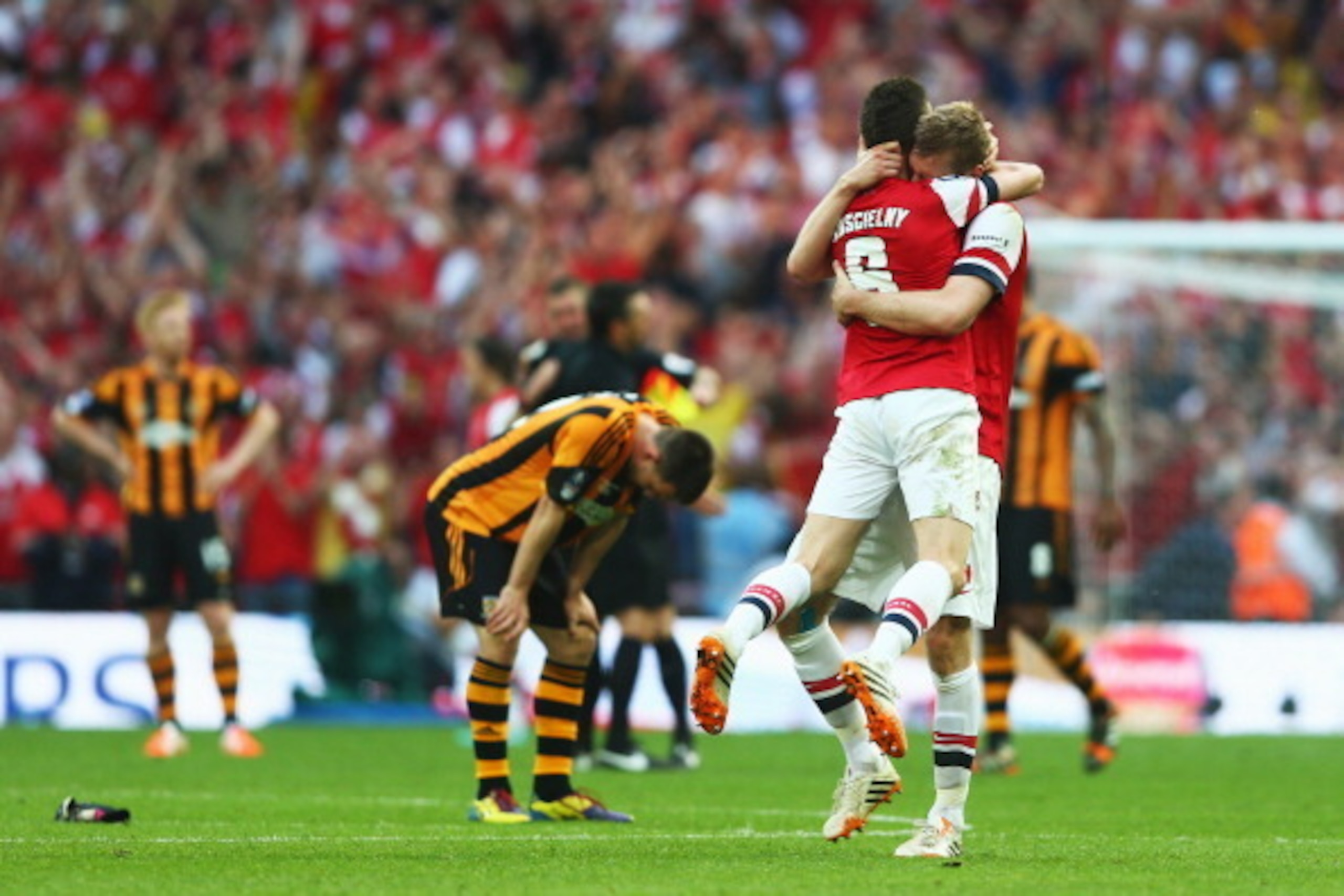LONDON, ENGLAND - MAY 17:  Despair for Hull City as Laurent Koscielny and Per Mertesacker of Arsenal celebrate victory after the FA Cup with Budweiser Final match between Arsenal and Hull City at Wembley Stadium on May 17, 2014 in London, England.  (Photo