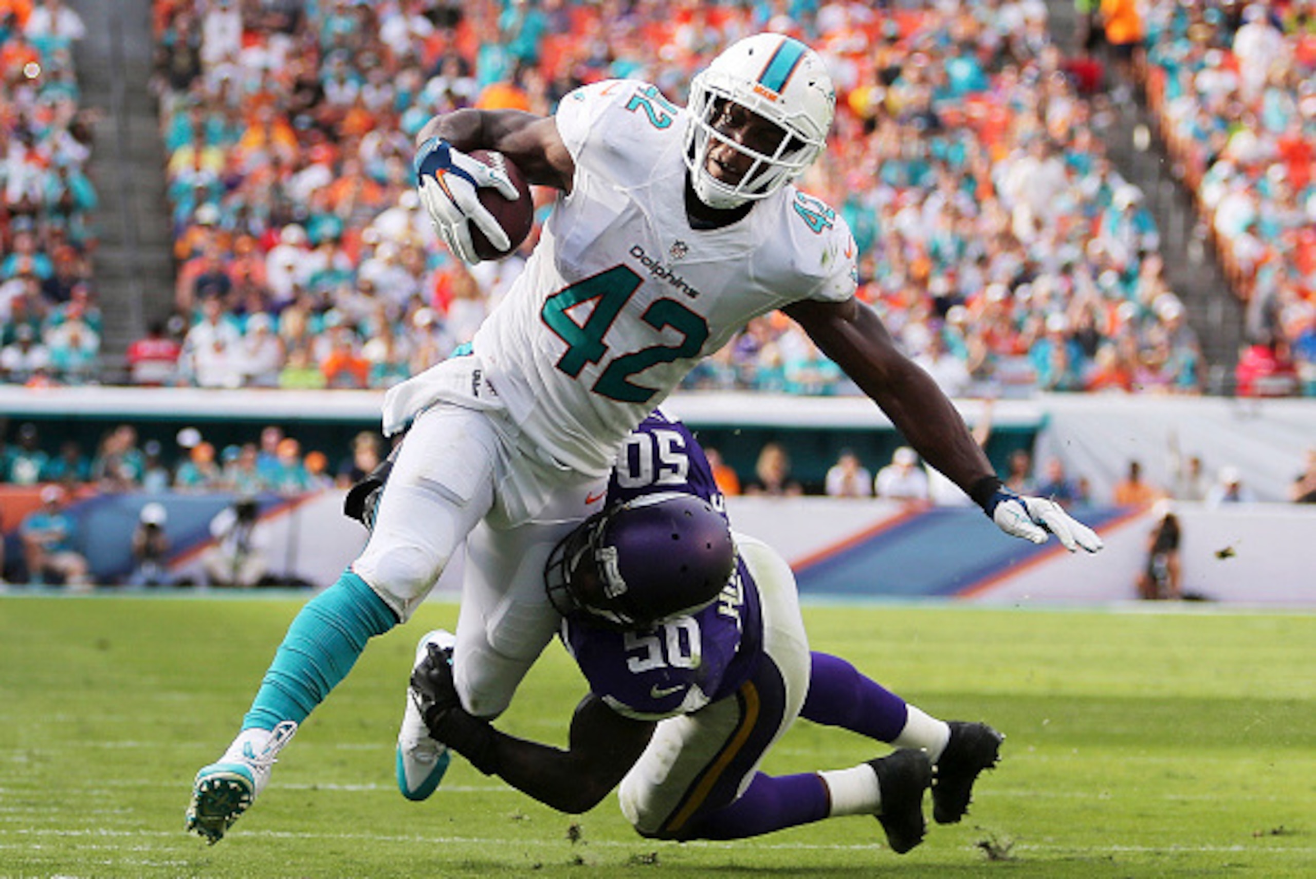 MIAMI GARDENS, FL - DECEMBER 21:  Tight end Charles Clay #42 of the Miami Dolphins is brought down by outside linebacker Gerald Hodges #50 of the Minnesota Vikings in the third quarter during a game at Sun Life Stadium on December 21, 2014 in Miami Garden