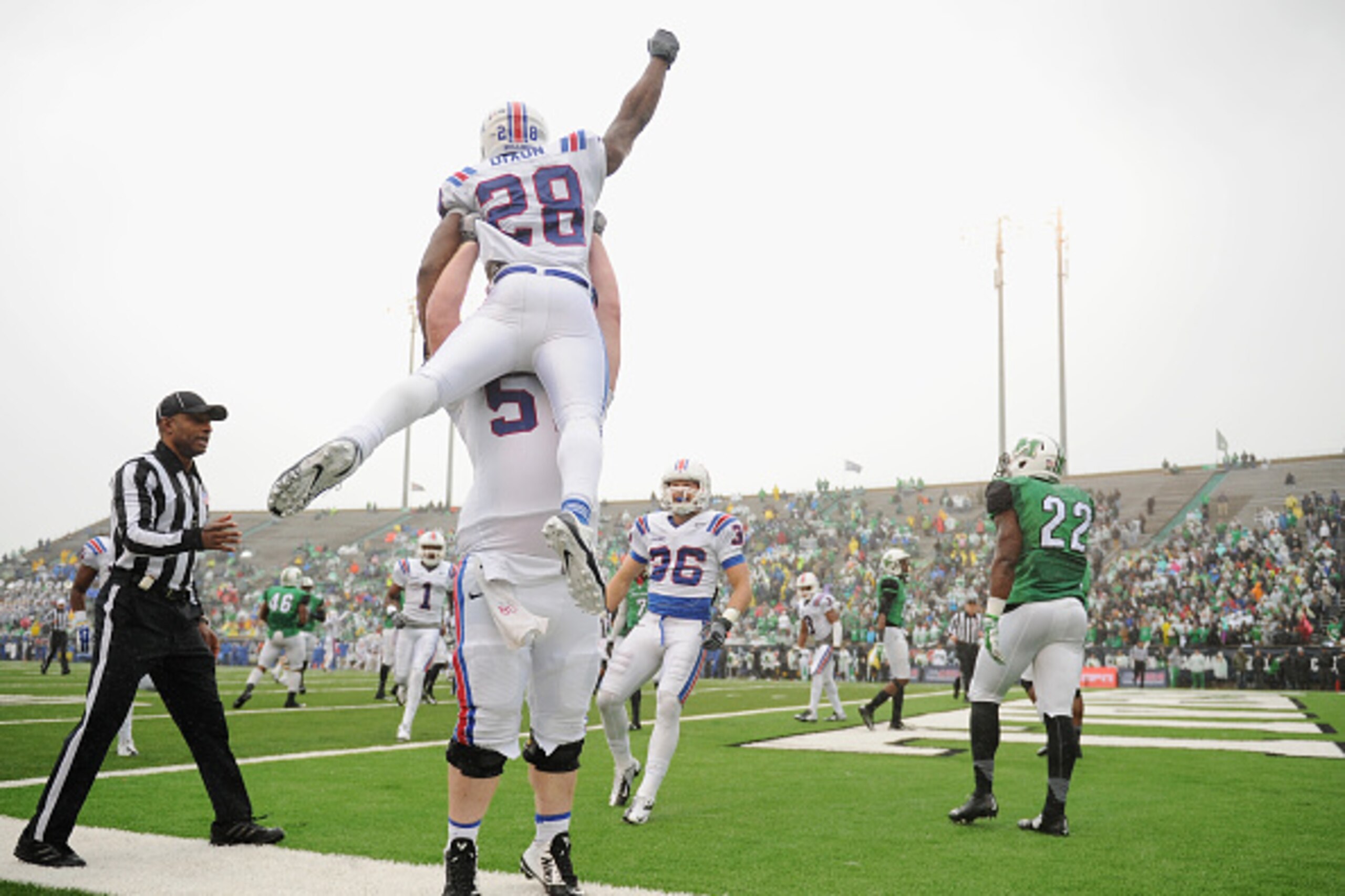 HUNTINGTON, WV - DECEMBER 06: Richard Greenwalt #57 picks up Kenneth Dixon #28 of the Louisiana Tech Bulldogs after Dixon scored a touchdown in the first quarter against the Marshall Thundering Herd at Joan C. Edwards Stadium during the Conference USA cha