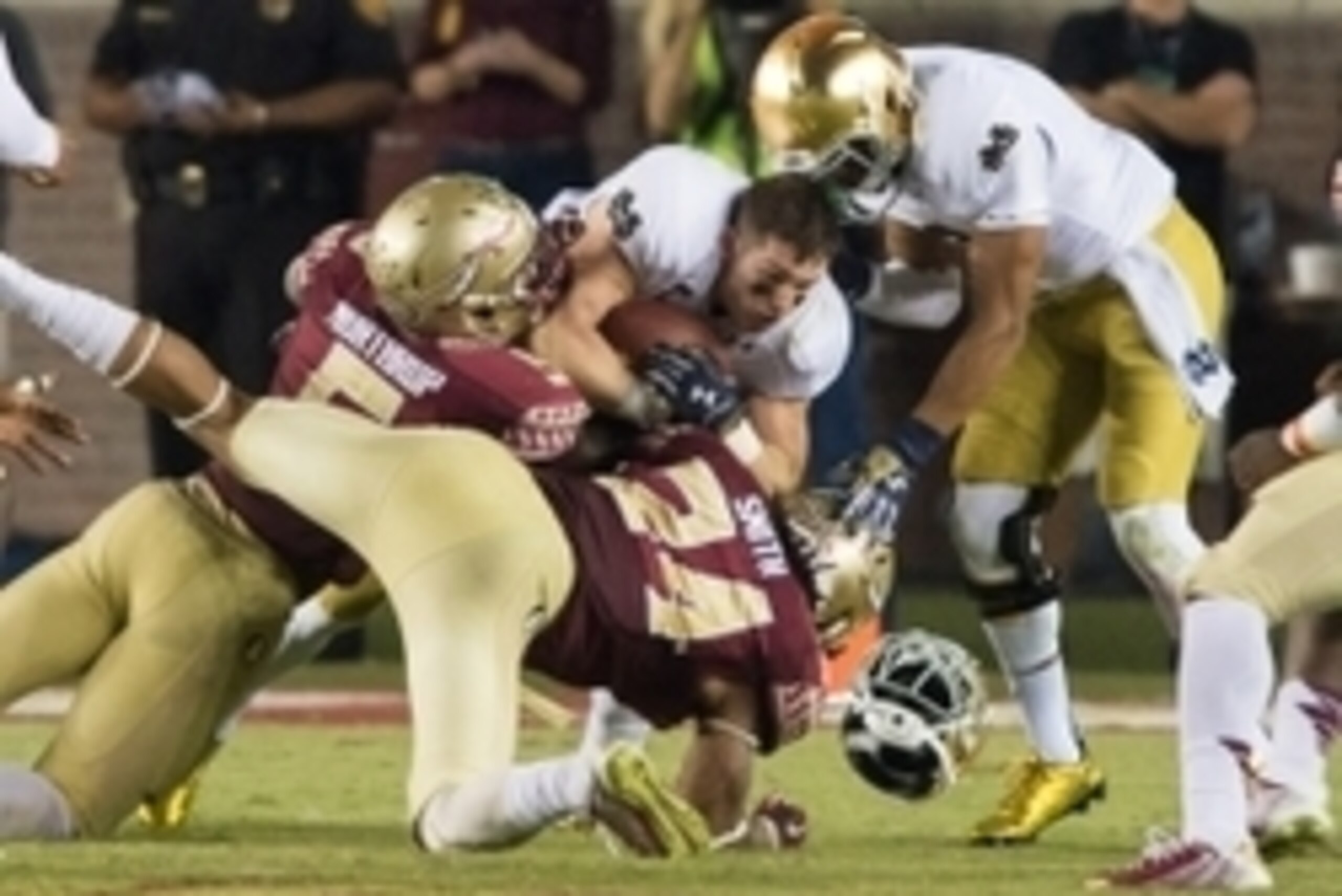 Oct 18, 2014; Tallahassee, FL, USA; Notre Dame Fighting Irish running back Cam McDaniel (33) loses his helmet after being hit by Florida State Seminoles linebacker Reggie Northrup (5) and linebacker Terrance Smith (24) in the third quarter at Doak Campbel