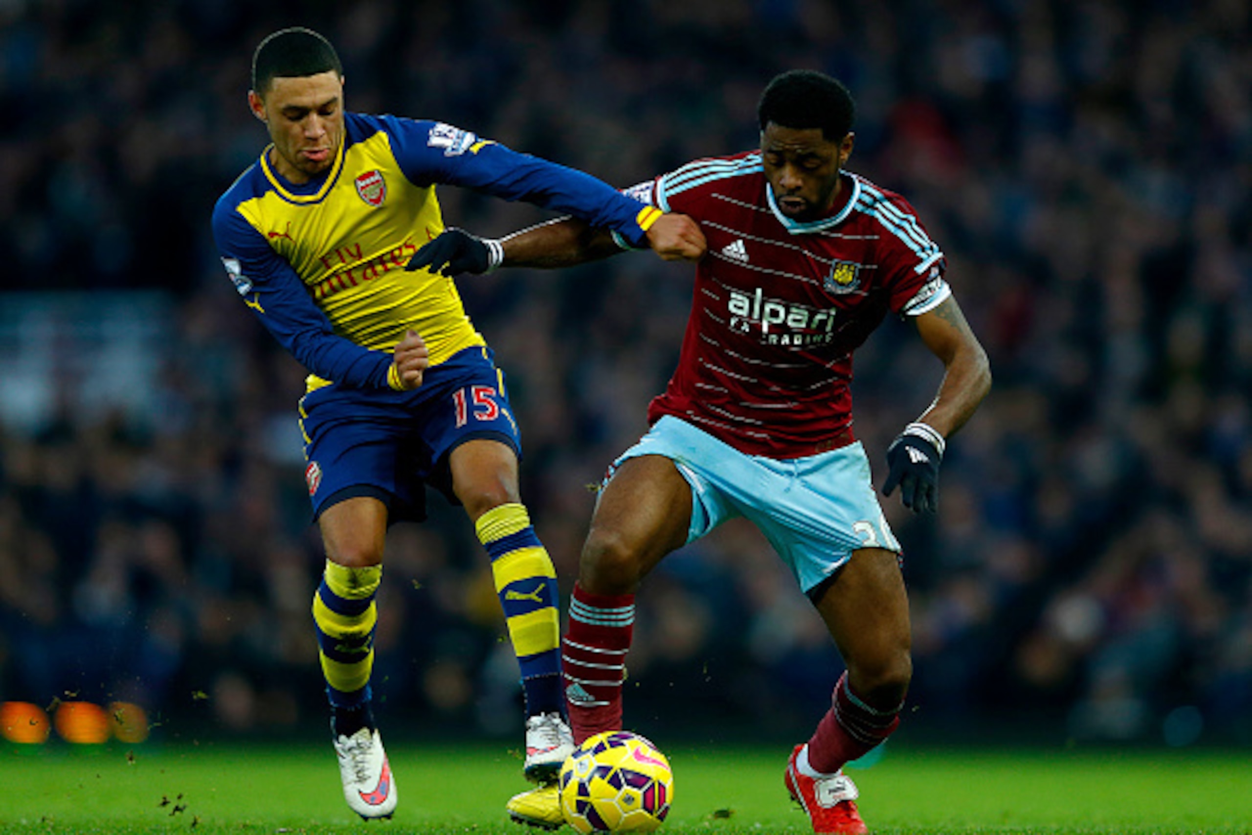 LONDON, ENGLAND - DECEMBER 28: Alexandre Song of West Ham battles for the ball with Alex Oxlade-Chamberlain of Arsenal during the Barclays Premier League match between West Ham United and Arsenal at Boleyn Ground on December 28, 2014 in London, England. LONDON, ENGLAND - DECEMBER 28: Alexandre Song of West Ham battles for the ball with Alex Oxlade-Chamberlain of Arsenal during the Barclays Premier League match between West Ham United and Arsenal at Boleyn Ground on December 28, 2014 in London, England.