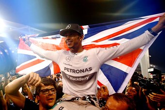 ABU DHABI, UNITED ARAB EMIRATES - NOVEMBER 23:   (EDITORS NOTE: Retransmission of #459457336) Lewis Hamilton of Great Britain and Mercedes GP celebrates with his team after winning the World Championship after the Abu Dhabi Formula One Grand Prix at Yas M