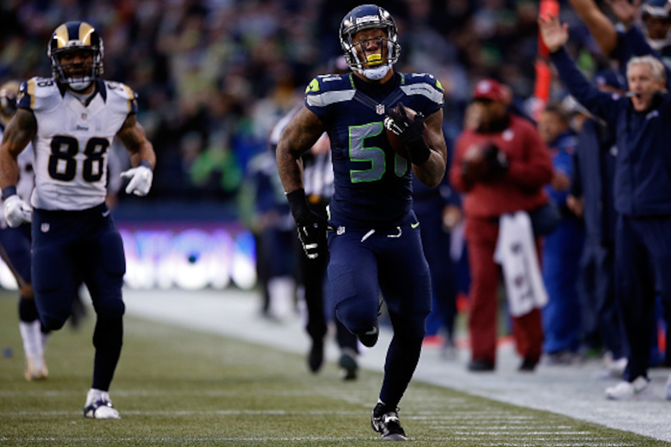 SEATTLE, WA - DECEMBER 28: Outside linebacker Bruce Irvin #51 of the Seattle Seahawks runs an interception back 49 yards for a touchdown as tight end Lance Kendricks #88 of the St. Louis Rams gives chase during the fourth quarter of the game against the S