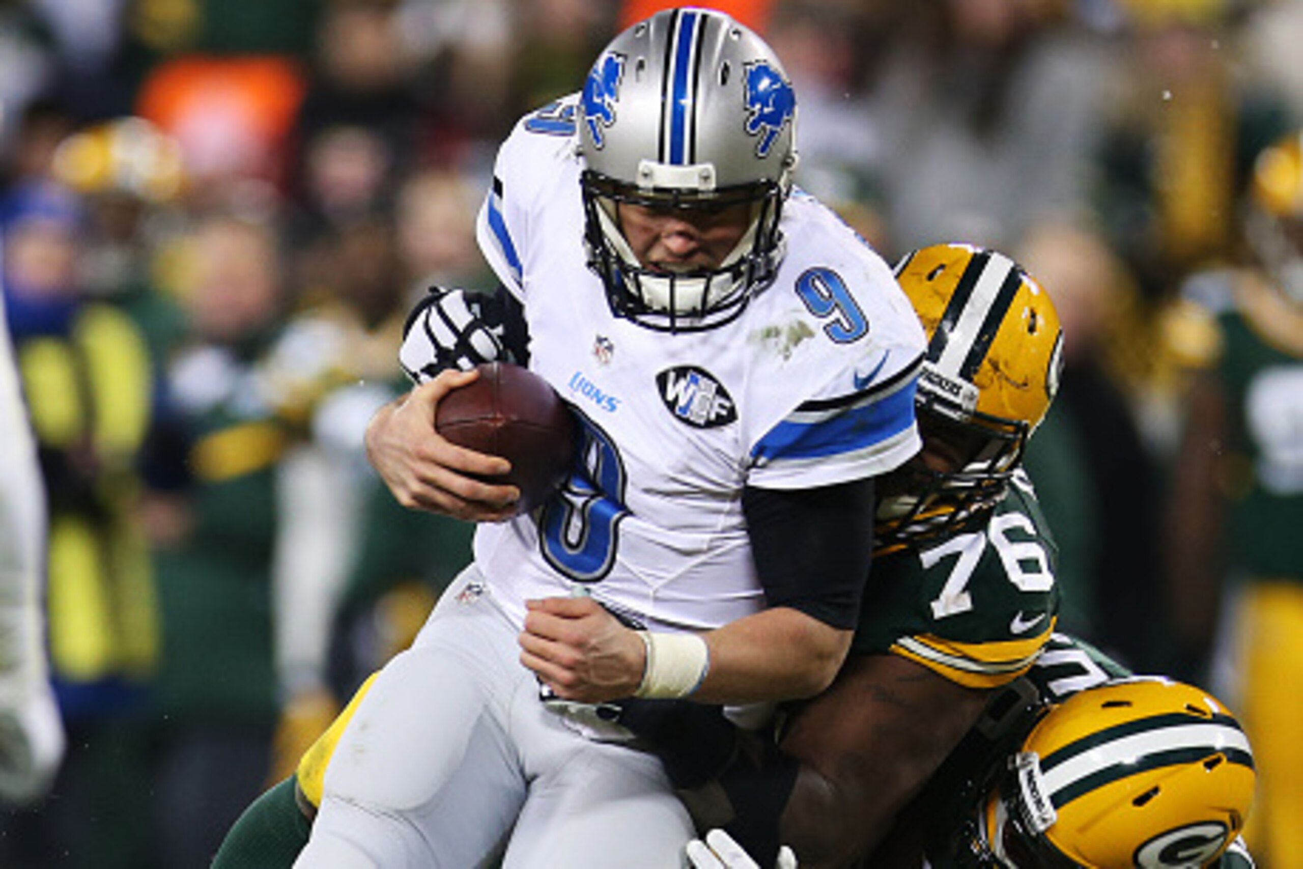 GREEN BAY, WI - DECEMBER 28: Matthew Stafford #9 of the Detroit Lions carries the ball for a first down as he is tackled by Mike Daniels #76 and Brad Jones #59 of the Green Bay Packers in the fourth quarter at Lambeau Field on December 28, 2014 in Gre GREEN BAY, WI - DECEMBER 28: Matthew Stafford #9 of the Detroit Lions carries the ball for a first down as he is tackled by Mike Daniels #76 and Brad Jones #59 of the Green Bay Packers in the fourth quarter at Lambeau Field on December 28, 2014 in Gre