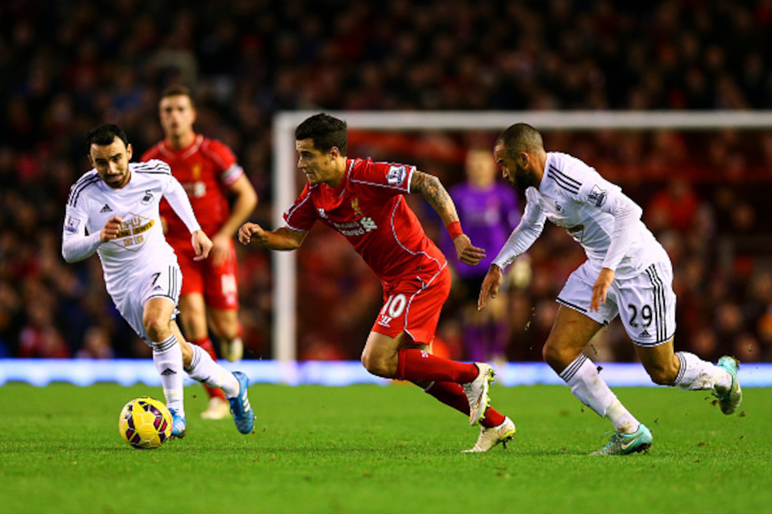 LIVERPOOL, ENGLAND - DECEMBER 29:  Philippe Coutinho of Liverpool runs with the ball past Ashley Richards and Leon Britton of Swansea City during the Barclays Premier League match between Liverpool and Swansea City at Anfield on December 29, 2014 in Liver
