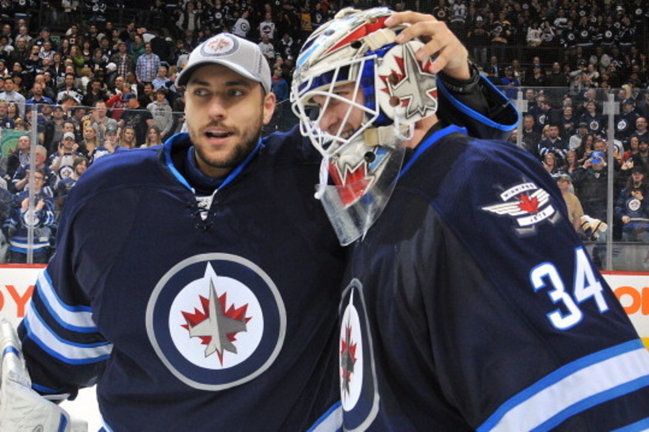 WINNIPEG, MB - APRIL 10: Goaltender Michael Hutchinson #34 of the Winnipeg Jets gets congratulated by teammate Ondrej Pavelec #31 after backstopping the Jets to a 2-1 shootout victory over the Boston Bruins in the final home game of the season at the MTS 