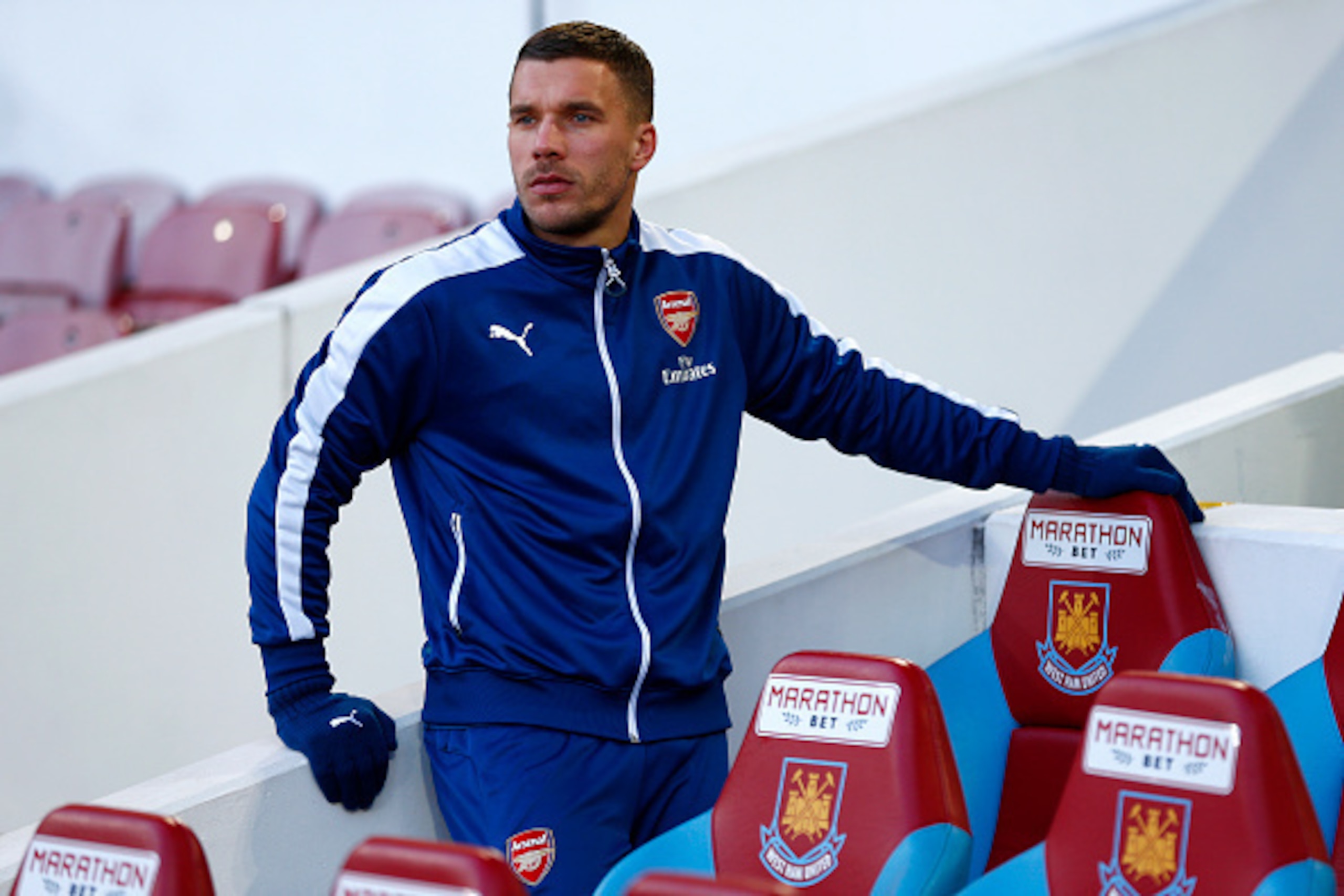 LONDON, ENGLAND - DECEMBER 28:  Lukas Podolski of Arsenal takes his seat on the bench before the Barclays Premier League match between West Ham United and Arsenal at Boleyn Ground on December 28, 2014 in London, England.  (Photo by Julian Finney/Getty Ima