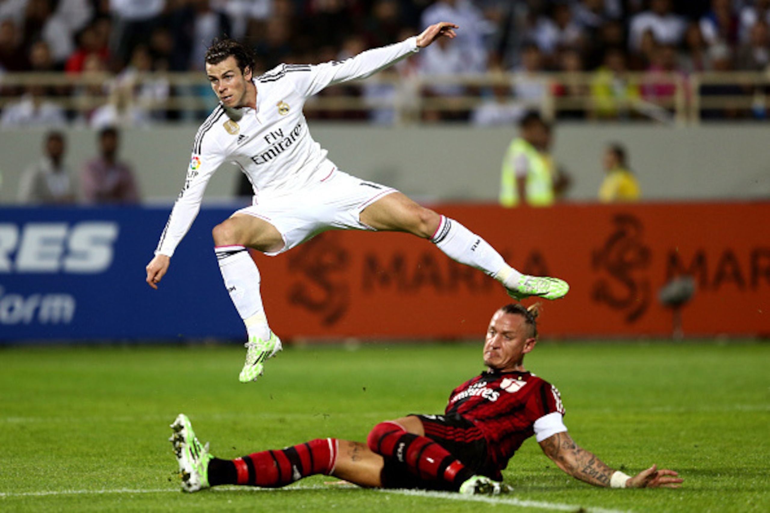 DUBAI, UNITED ARAB EMIRATES - DECEMBER 30:  Gareth Bale of Real Madrid strikes at goal as he is tackled by Philippe Mexes of AC Milan during the Dubai Football Challenge match between AC Milan and Real Madrid at The Sevens Stadium on December 30, 2014 in 