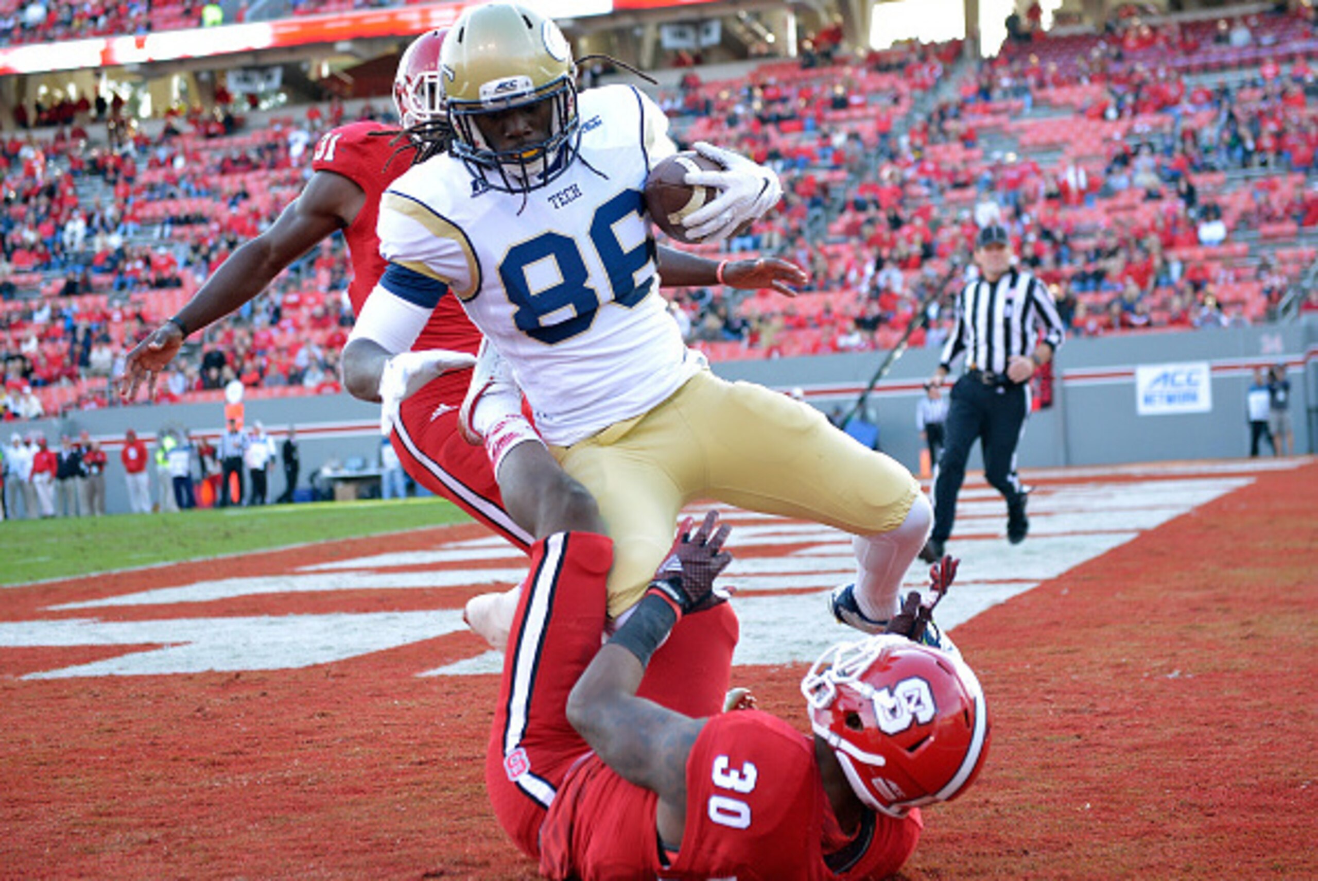 RALEIGH, NC - NOVEMBER 08:  Darren Waller #88 of the Georgia Tech Yellow Jackets beats defenders Mike Stevens #30 and Germaine Pratt #31 of the North Carolina State Wolfpack during their game at Carter-Finley Stadium on November 8, 2014 in Raleigh, North 
