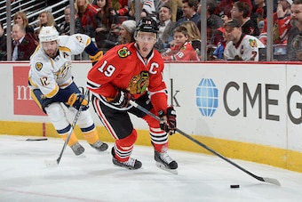 CHICAGO, IL - DECEMBER 29:  Jonathan Toews #19 of the Chicago Blackhawks takes control of the puck as Mike Fisher #12 of the Nashville Predators follows behind during the NHL game at the United Center on December 29, 2014 in Chicago, Illinois.  (Photo by 