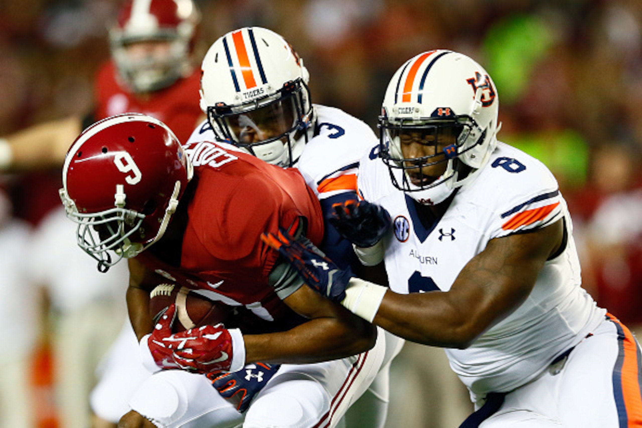 TUSCALOOSA, AL - NOVEMBER 29:  Amari Cooper #9 of the Alabama Crimson Tide catches a pass against Jonathan Jones #3 and Cassanova McKinzy #8 of the Auburn Tigers in the first quarter during the Iron Bowl at Bryant-Denny Stadium on November 29, 2014 in Tus