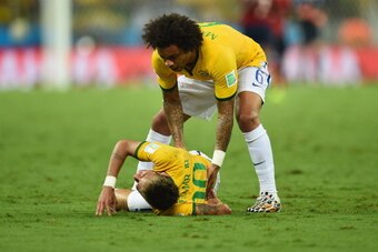 FORTALEZA, BRAZIL - JULY 04:  Neymar of Brazil lies on the field after a challenge as teammate Marcelo reacts during the 2014 FIFA World Cup Brazil Quarter Final match between Brazil and Colombia at Castelao on July 4, 2014 in Fortaleza, Brazil.  (Photo b