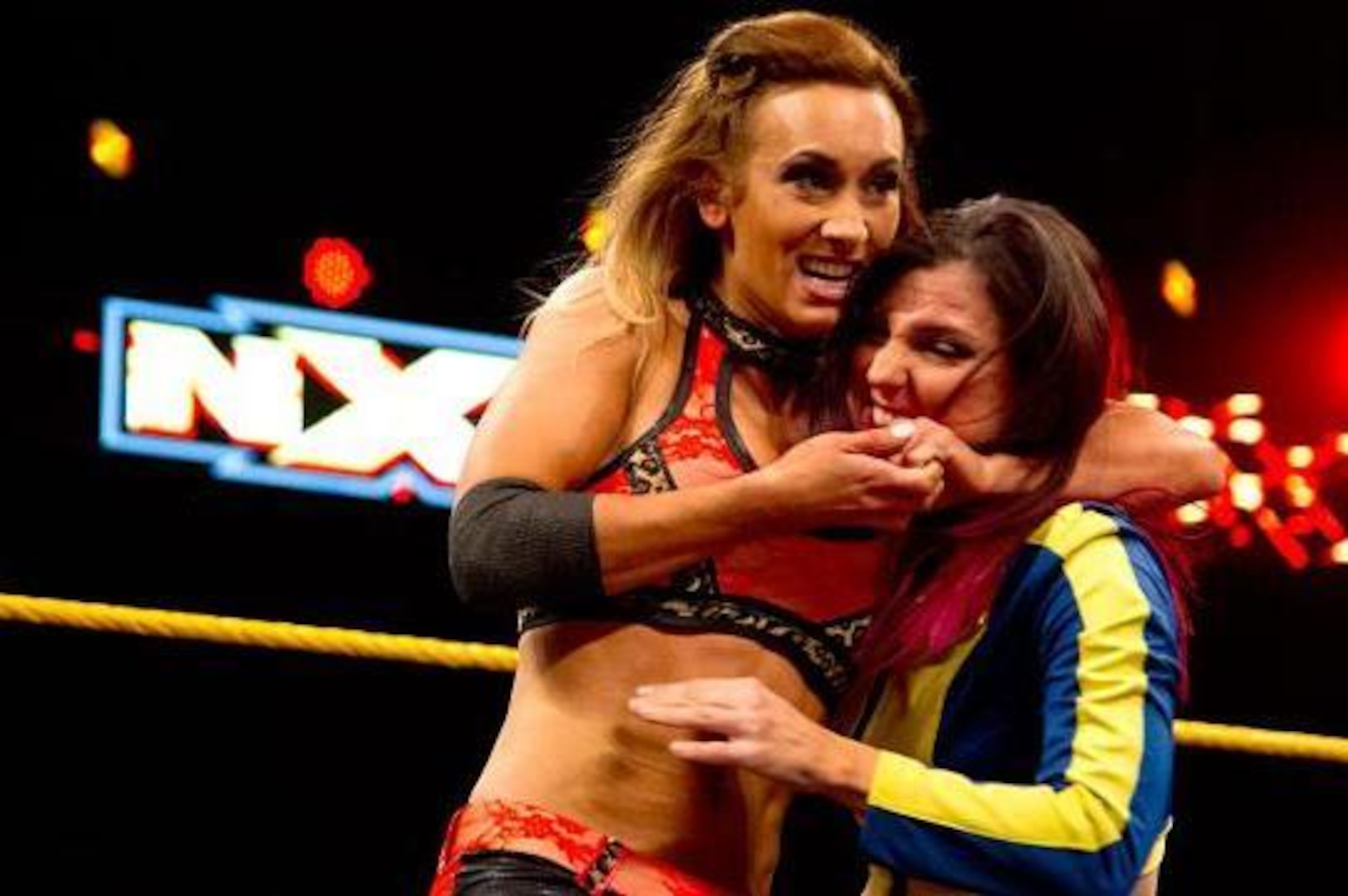 Carmella puts Blue Pants in a headlock.