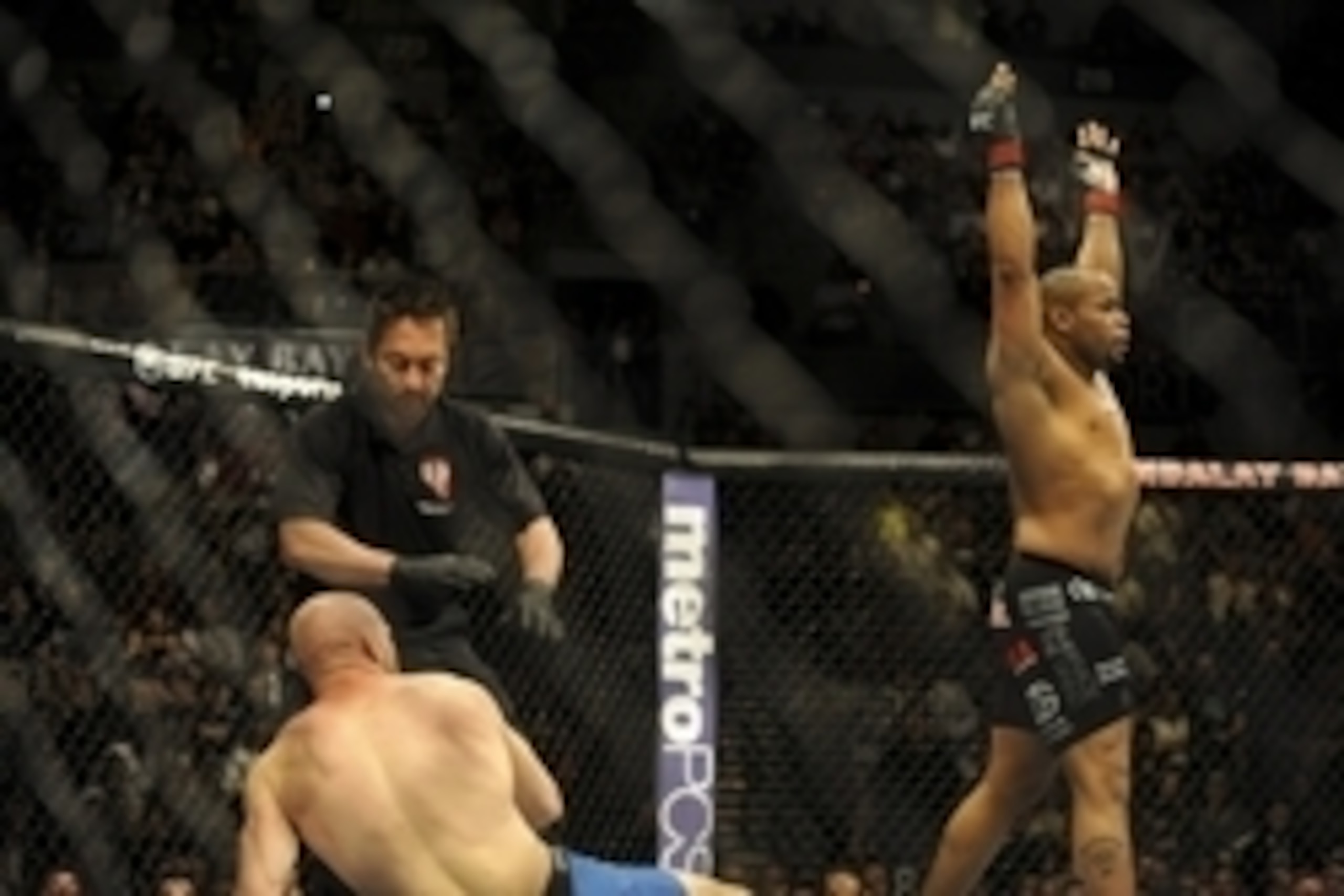 Feb 22, 2014; Las Vegas, NV, USA; Patrick Cummins (blue gloves) throws his hands up as Daniel Cormier lies on the mat after the referee stops their UFC light heavyweight bout at Mandalay Bay. Cormier won by way of a TKO in the first round. Mandatory Credi