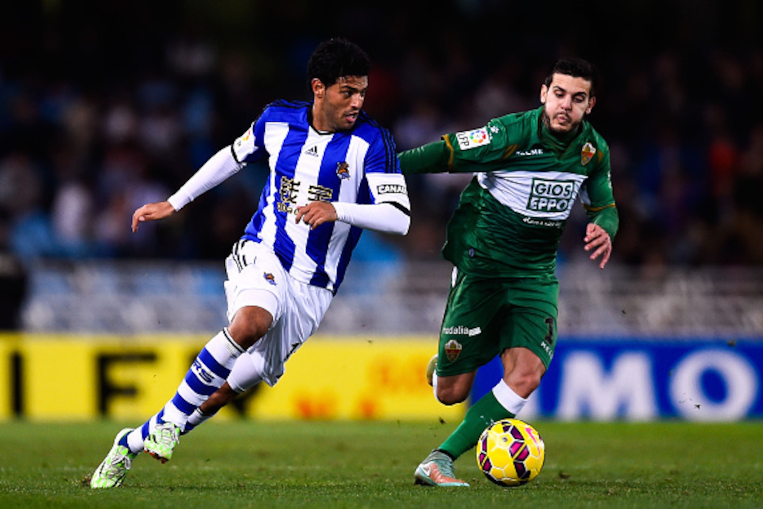SAN SEBASTIAN, SPAIN - NOVEMBER 28:  Carlos Vela Garrido of Real Sociedad competes for the ball with Victor Rodriguez of Elche FC during the La Liga match between Real Socided and Elche FC at Estadio Anoeta on November 28, 2014 in San Sebastian, Spain.  (