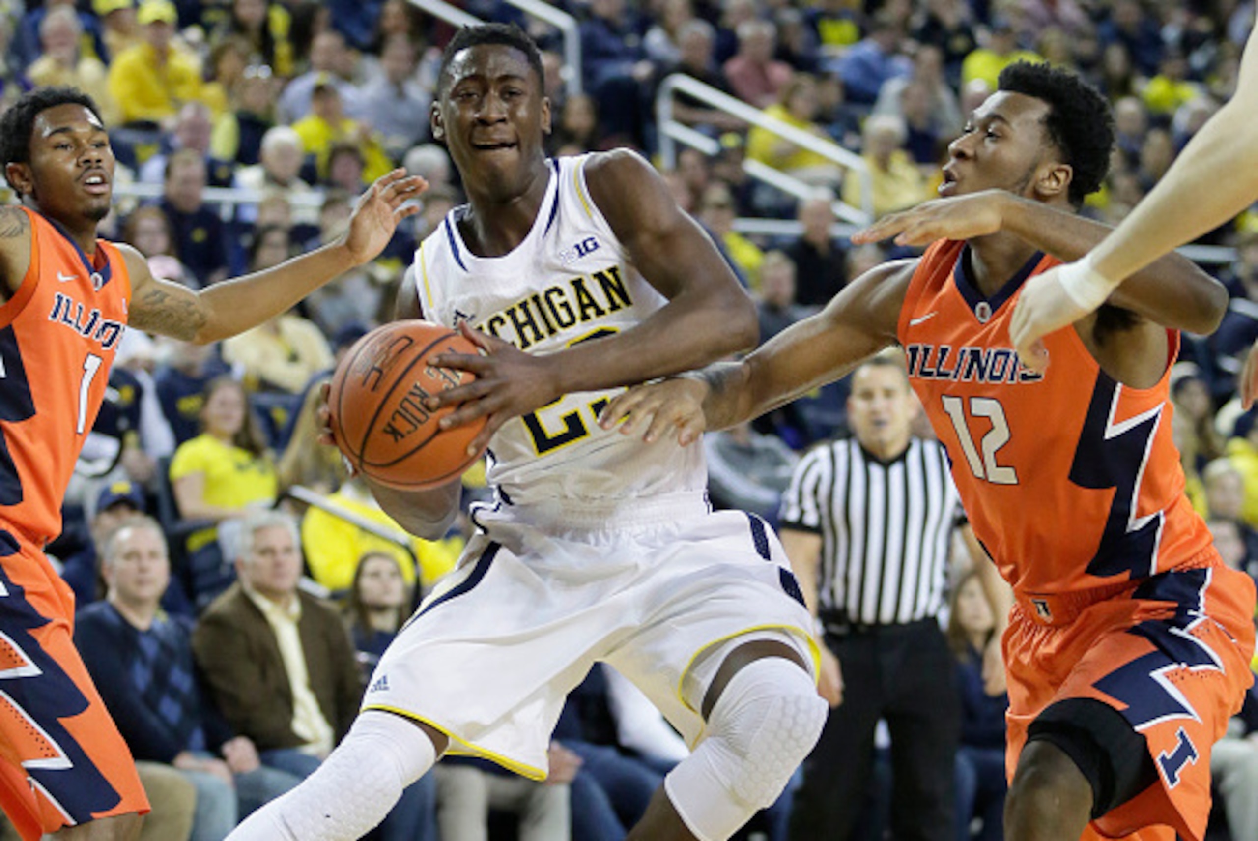 ANN ARBOR, MI - DECEMBER 30:  Caris LeVert #23 of the Michigan Wolverines goes to the basket against Leron Black #12 of the Illinois Fighting Illini during the first half at Crisler Arena on December 30, 2014 in Ann Arbor, Michigan. (Photo by Duane Burles