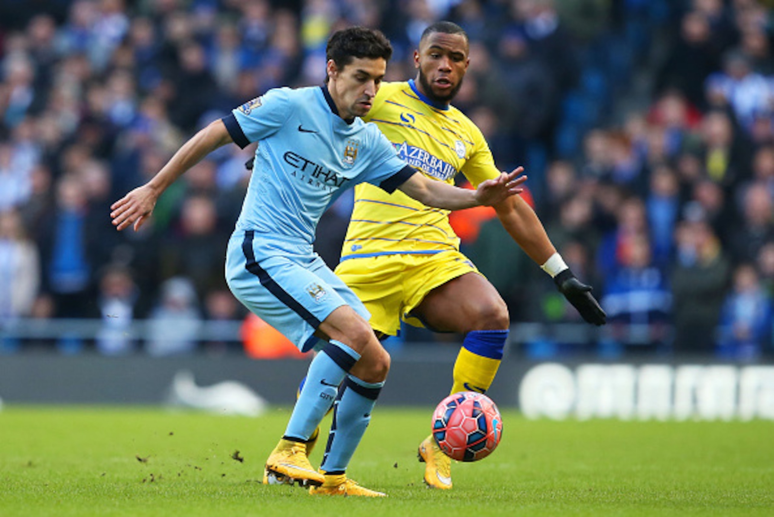 MANCHESTER, ENGLAND - JANUARY 04:  Jesus Navas of Manchester City is closed down by Claude Dielna of Sheffield Wednesday during the FA Cup Third Round match between  Manchester City and Sheffield Wednesday at Etihad Stadium on January 4, 2015 in Mancheste