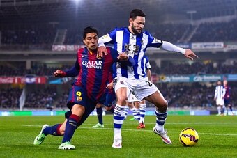 SAN SEBASTIAN, SPAIN - JANUARY 04:  Andres Iniesta of FC Barcelona competes for the ball with Alberto de la Bella of Real Sociedad during the La Liga match between Real Sociedad de Futbol and FC Barcelona at Estadio Anoeta on January 4, 2015 in San Sebast