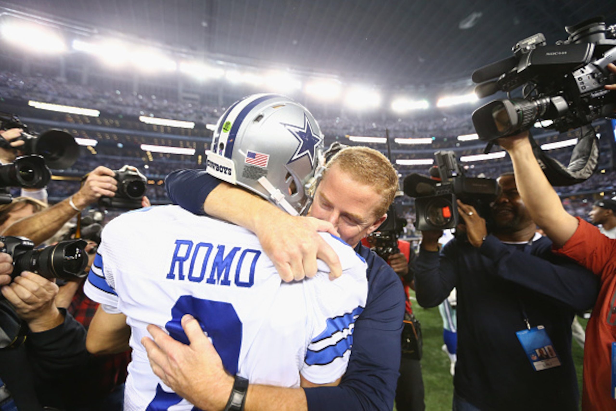 ARLINGTON, TX - JANUARY 04:  Tony Romo #9 of the Dallas Cowboys hugs coach Jason Garrett after their 24-20 win against the Detroit Lions in their NFC Wild Card Playoff game at AT&T Stadium on January 4, 2015 in Arlington, Texas.  (Photo by Ronald Martinez