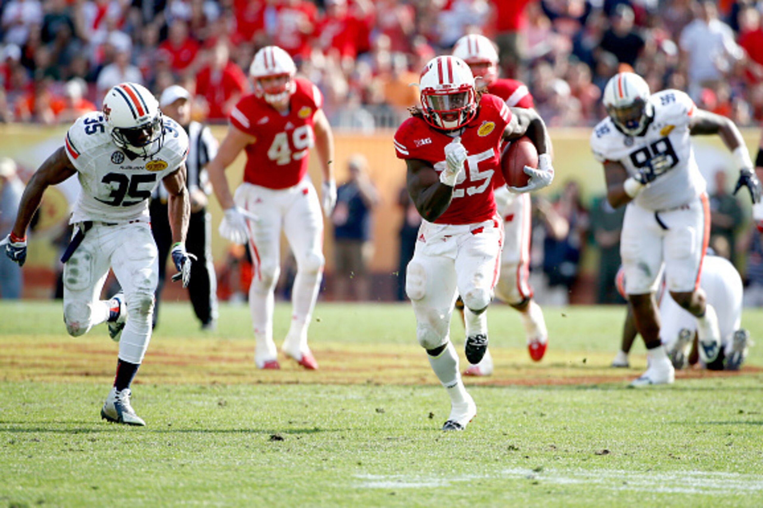 TAMPA, FL - JANUARY 1:  Running back Melvin Gordon #25 of the Wisconsin Badgers out runs defensive back Jermaine Whitehead #35 of the Auburn Tigers as he runs 53 yards for a touchdown during the third quarter of the Outback Bowl on January 1, 2015 at Raym