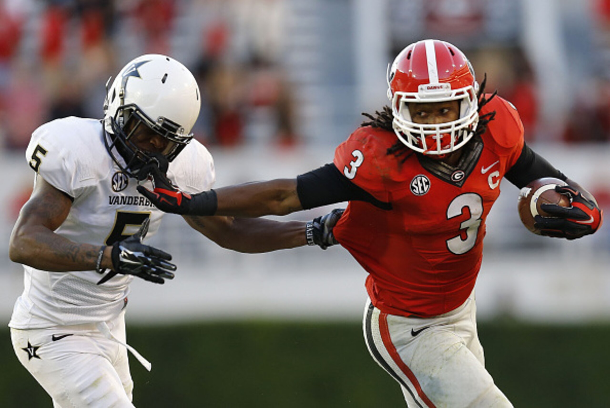 ATHENS, GA - OCTOBER 04:  Running back Todd Gurley #3 of the Georgia Bulldogs stiff arms cornerback Torren McGaster #5 of the Vanderbilt Commodores during a running playin the game at Sanford Stadium on October 4, 2014 in Athens, Georgia.  (Photo by Mike 