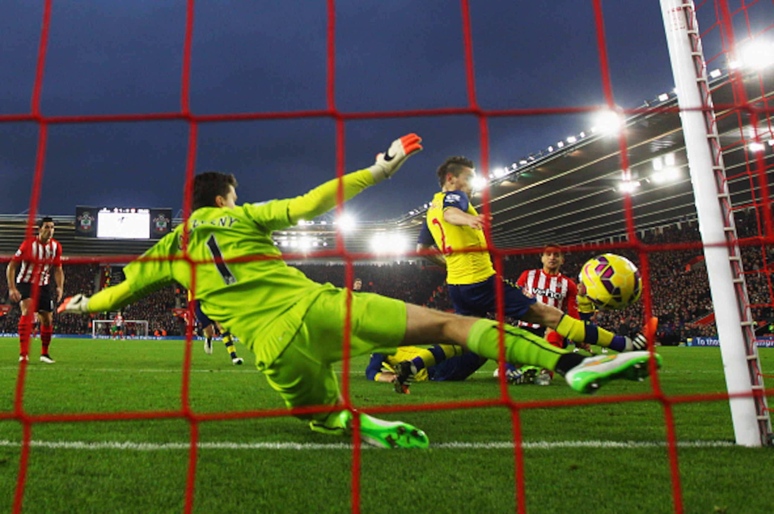SOUTHAMPTON, ENGLAND - JANUARY 01:  Dusan Tadic of Southampton (R) scores their second goal past Wojciech Szczesny (1) and Mathieu Debuchy of Arsenal (2) during the Barclays Premier League match between Southampton and Arsenal at St Mary's Stadium on Janu