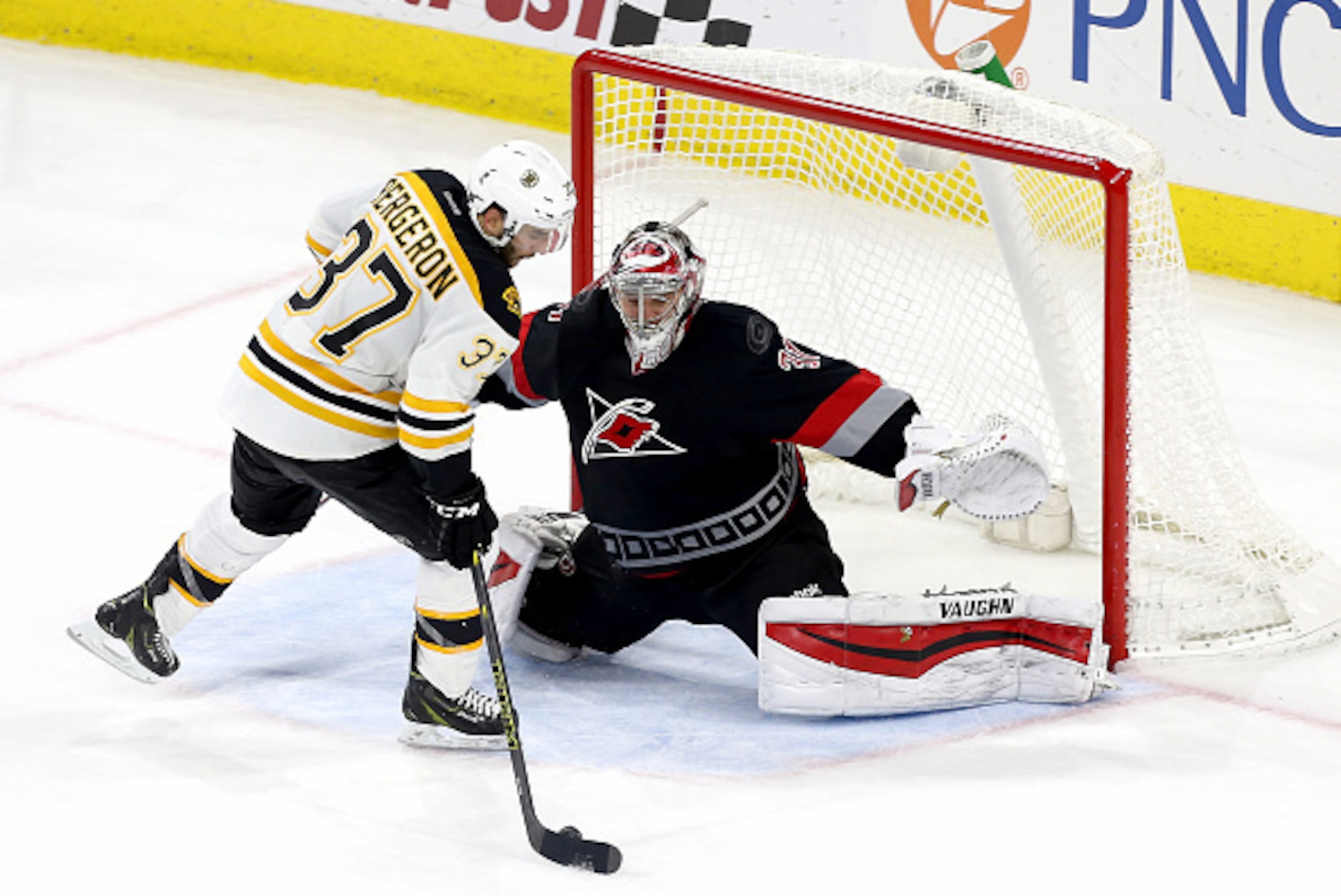 RALEIGH, NC - JANUARY 04: Anton Khudobin #31 of the Carolina Hurricanes makes a save on a shot by Patrice Bergeron #37 of the Boston Bruins in a shootout during their NHL game at PNC Arena on January 4, 2015 in Raleigh, North Carolina.  (Photo by Gregg Fo