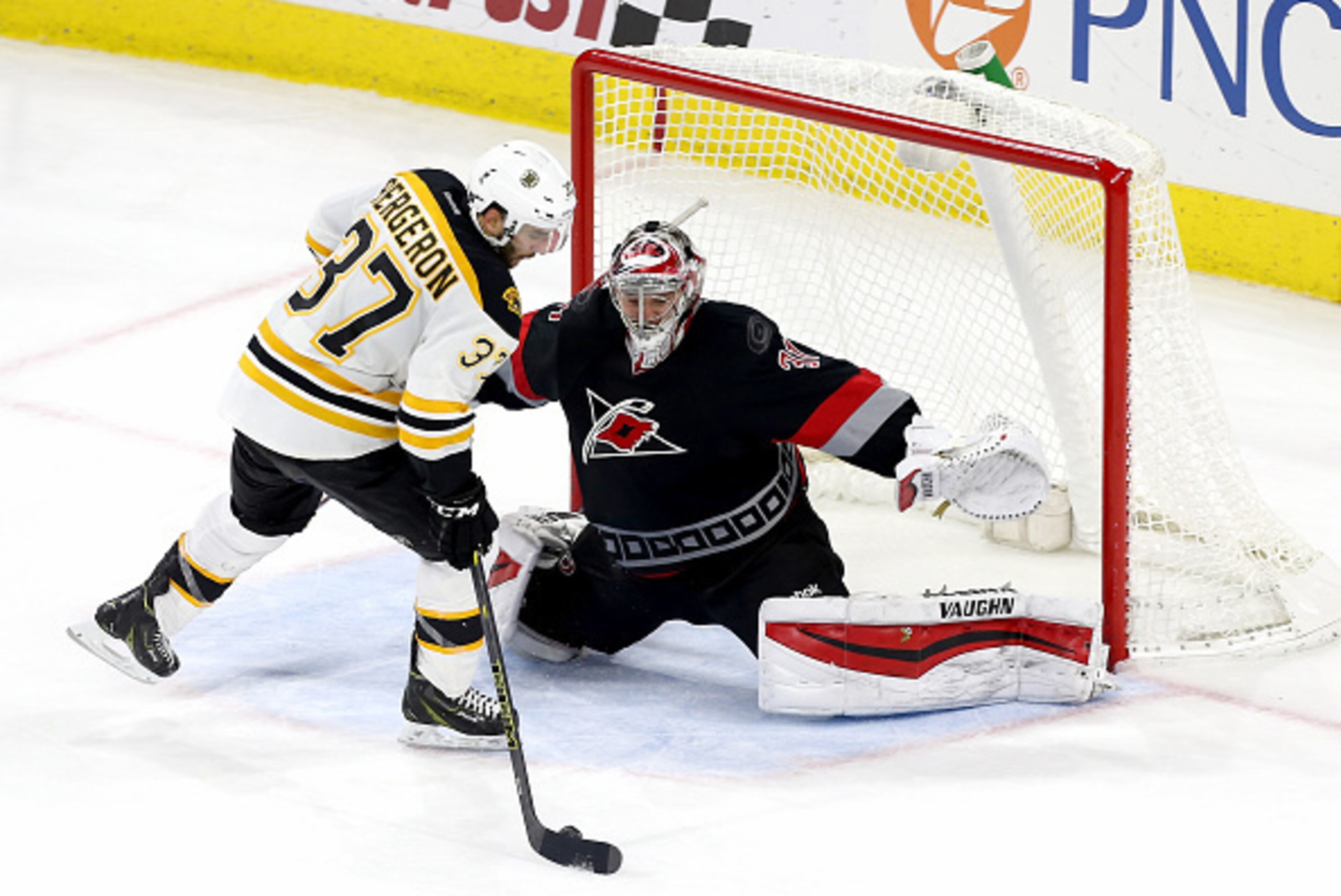RALEIGH, NC - JANUARY 04: Anton Khudobin #31 of the Carolina Hurricanes makes a save on a shot by Patrice Bergeron #37 of the Boston Bruins in a shootout during their NHL game at PNC Arena on January 4, 2015 in Raleigh, North Carolina.  (Photo by Gregg Fo