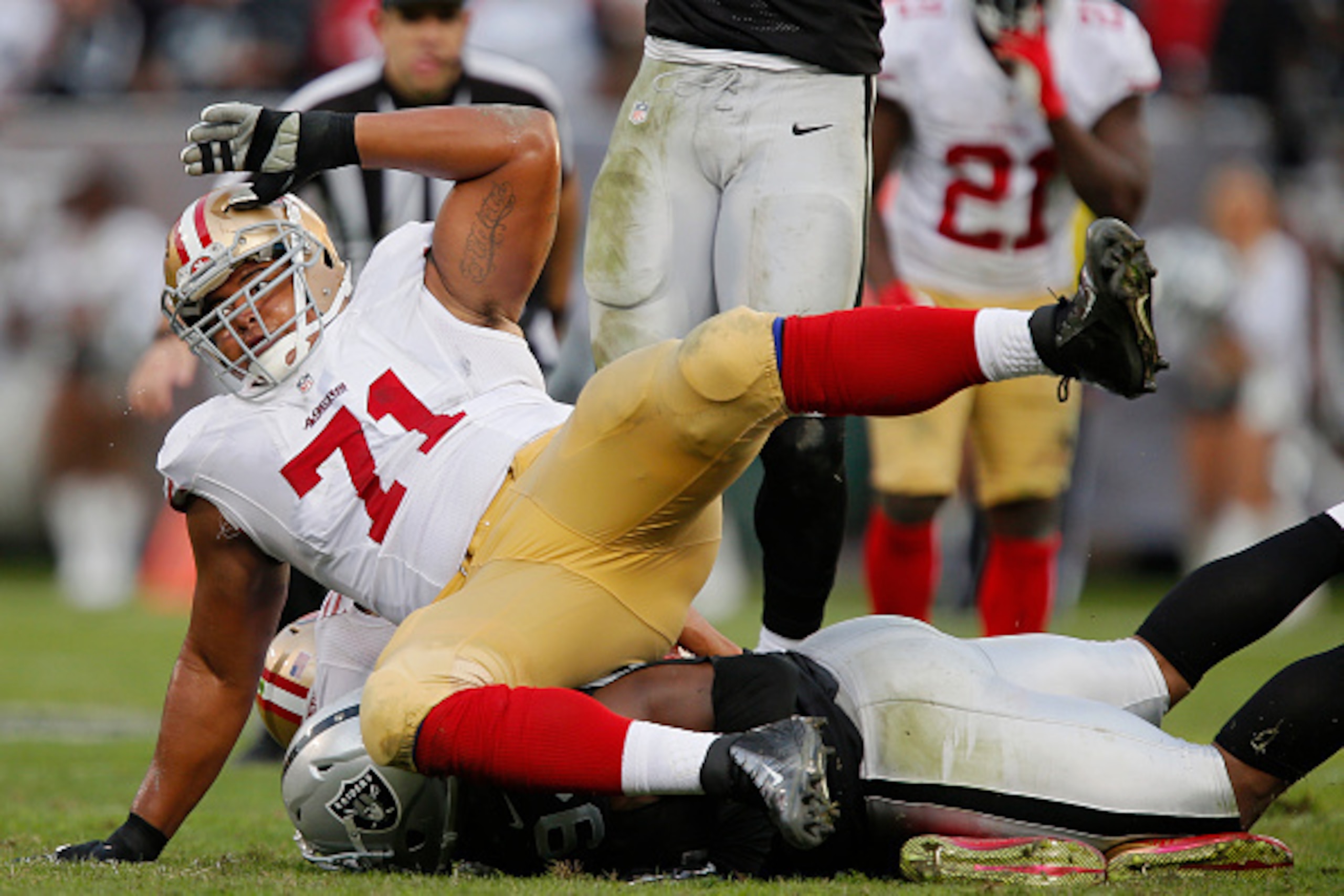 OAKLAND, CA - DECEMBER 7:  Tackle Jonathan Martin #71 of the San Francisco 49ers falls with an injury as Antonio Smith #94 of the Oakland Raiders sacks quarterback Colin Kaepernick #7 of the 49ers on December 7, 2014 at O.co Coliseum in Oakland, Californi