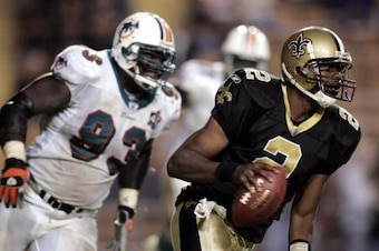 BATON ROUGE, LA - OCTOBER 30:  Quarterback Aaron Brooks #2 of the New Orleans Saints scrambles around Kevin Carter #93 of the Miami Dolphins on October 30, 2005 at Tiger Stadium on the Louisiana State University campus in Baton Rouge, Louisiana.  The Dolp