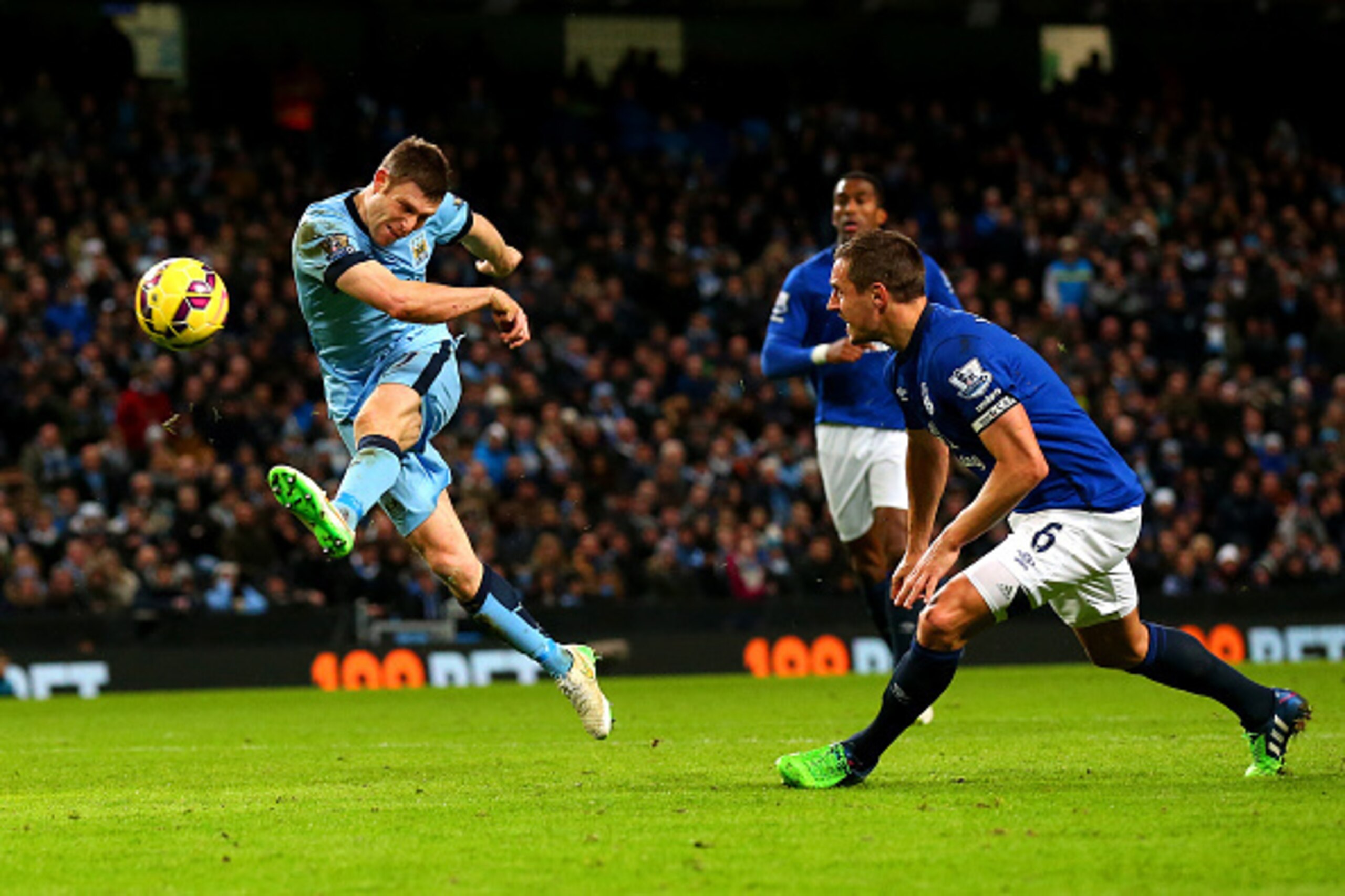 MANCHESTER, ENGLAND - DECEMBER 06:  James Milner of Manchester City shoots at goal under pressure from Phil Jagielka of Everton during the Barclays Premier League match between Manchester City and Everton at Etihad Stadium on December 6, 2014 in Mancheste