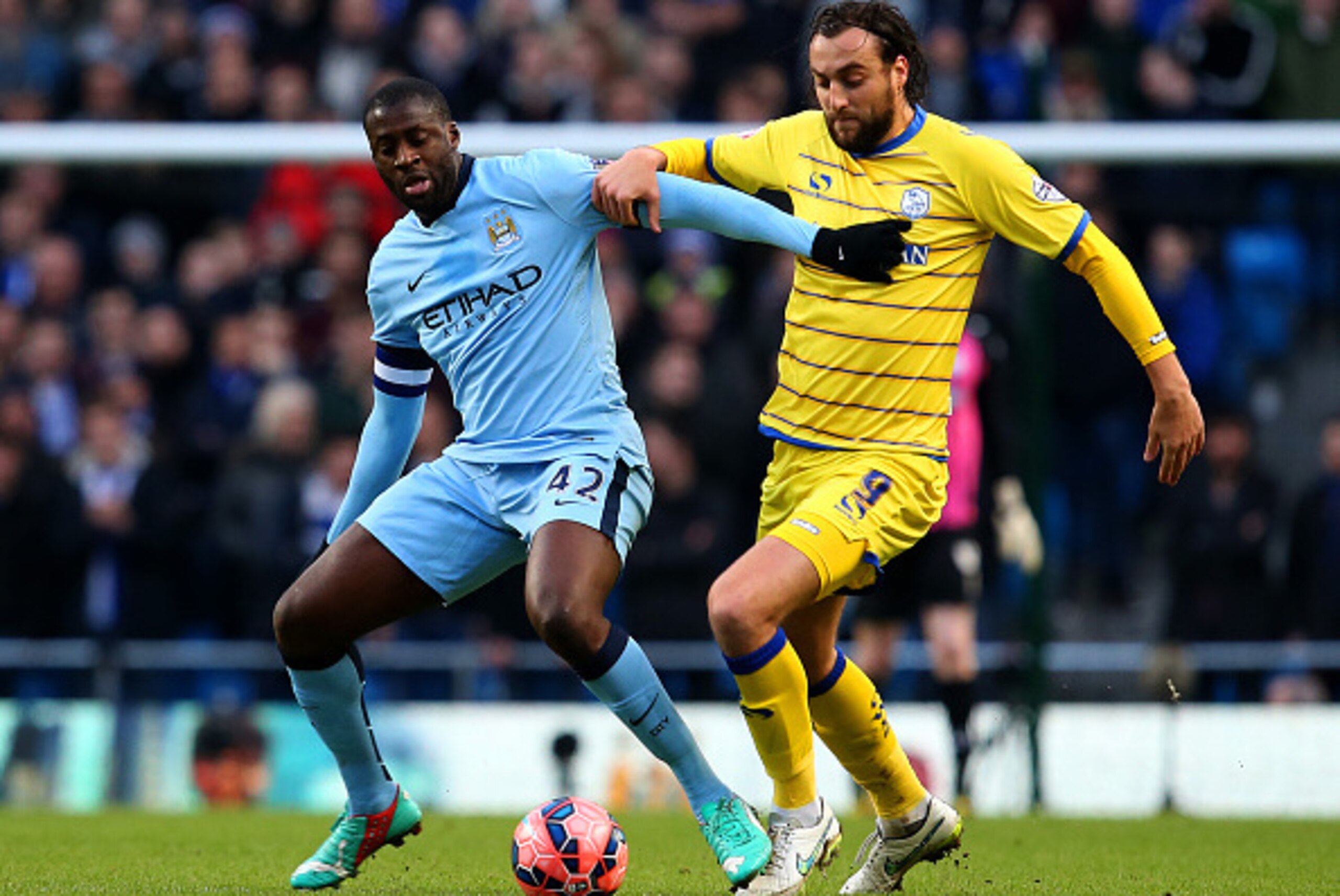 MANCHESTER, ENGLAND - JANUARY 04:  Yaya Toure of Manchester City and Atdhe Nuhiu of Sheffield Wednesday battle for the ball during the FA Cup Third Round match between  Manchester City and Sheffield Wednesday at Etihad Stadium on January 4, 2015 in Manche