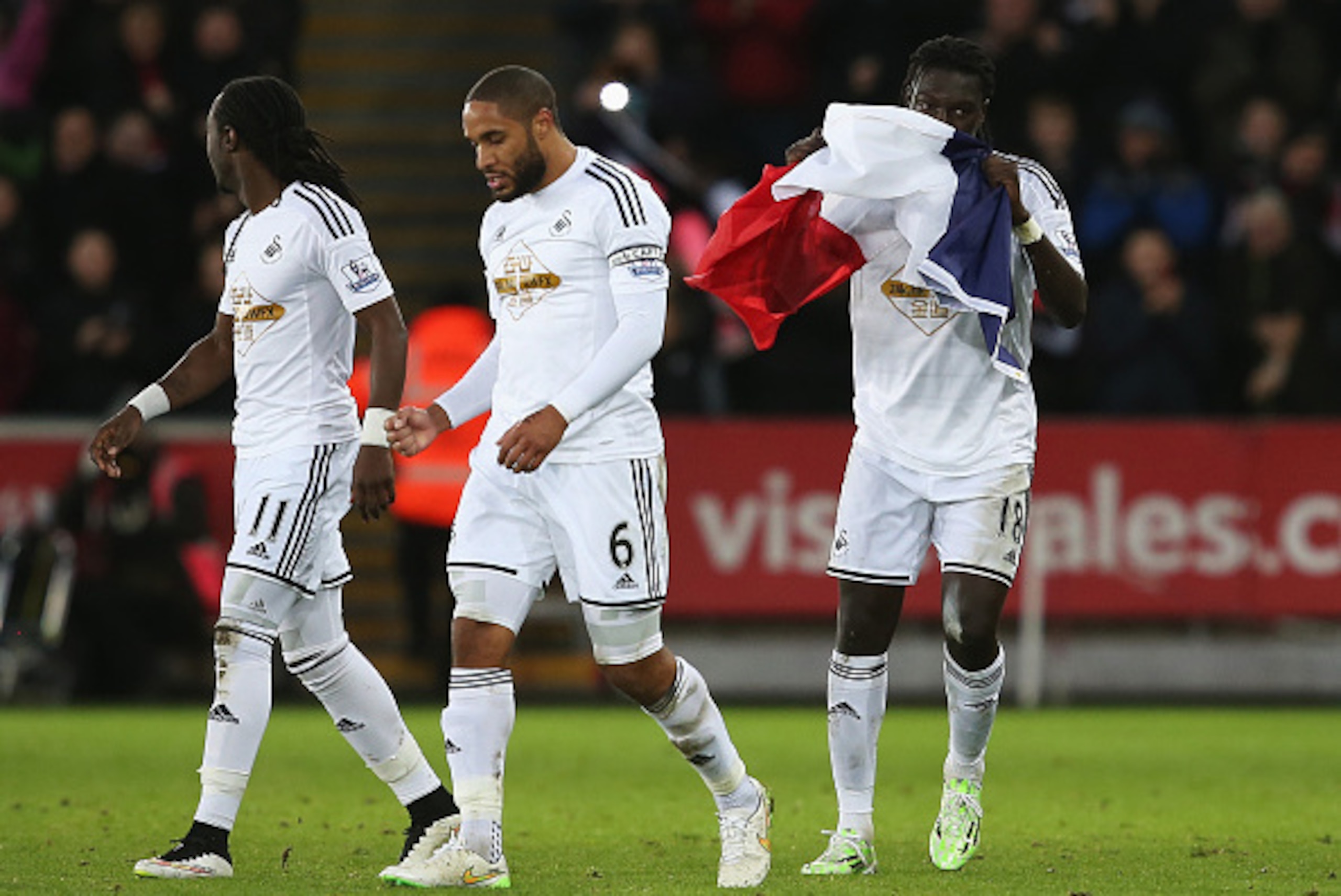 SWANSEA, WALES - JANUARY 10:  Bafetibi Gomis of Swansea celebrates his team's second goal with the French flag during the Barclays Premier League match between Swansea City and West Ham United at Liberty Stadium on January 10, 2015 in Swansea, Wales.  (Ph
