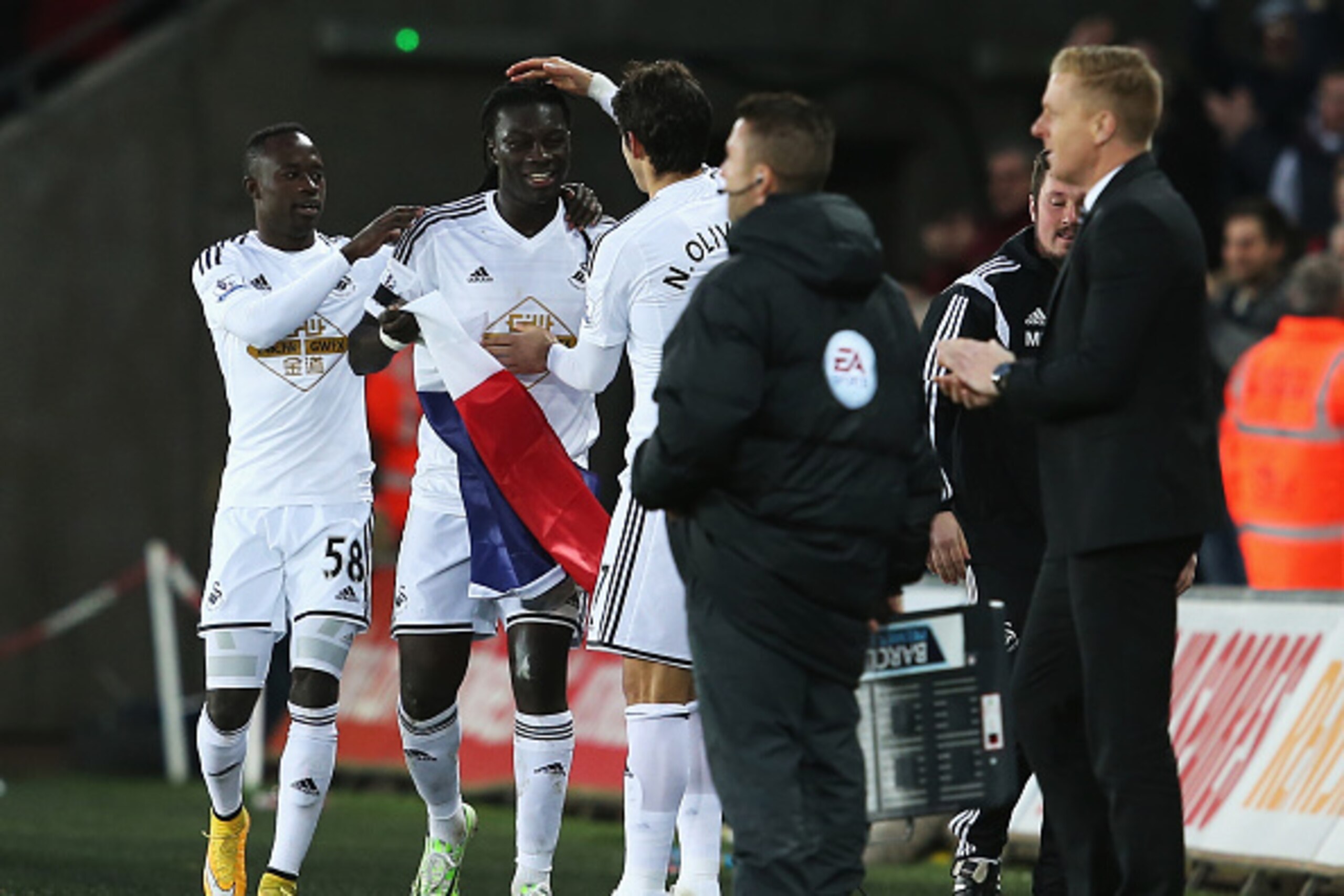 SWANSEA, WALES - JANUARY 10:  Bafetibi Gomis of Swansea celebrates his team's second goal with the French flag and team mates during the Barclays Premier League match between Swansea City and West Ham United at Liberty Stadium on January 10, 2015 in Swans
