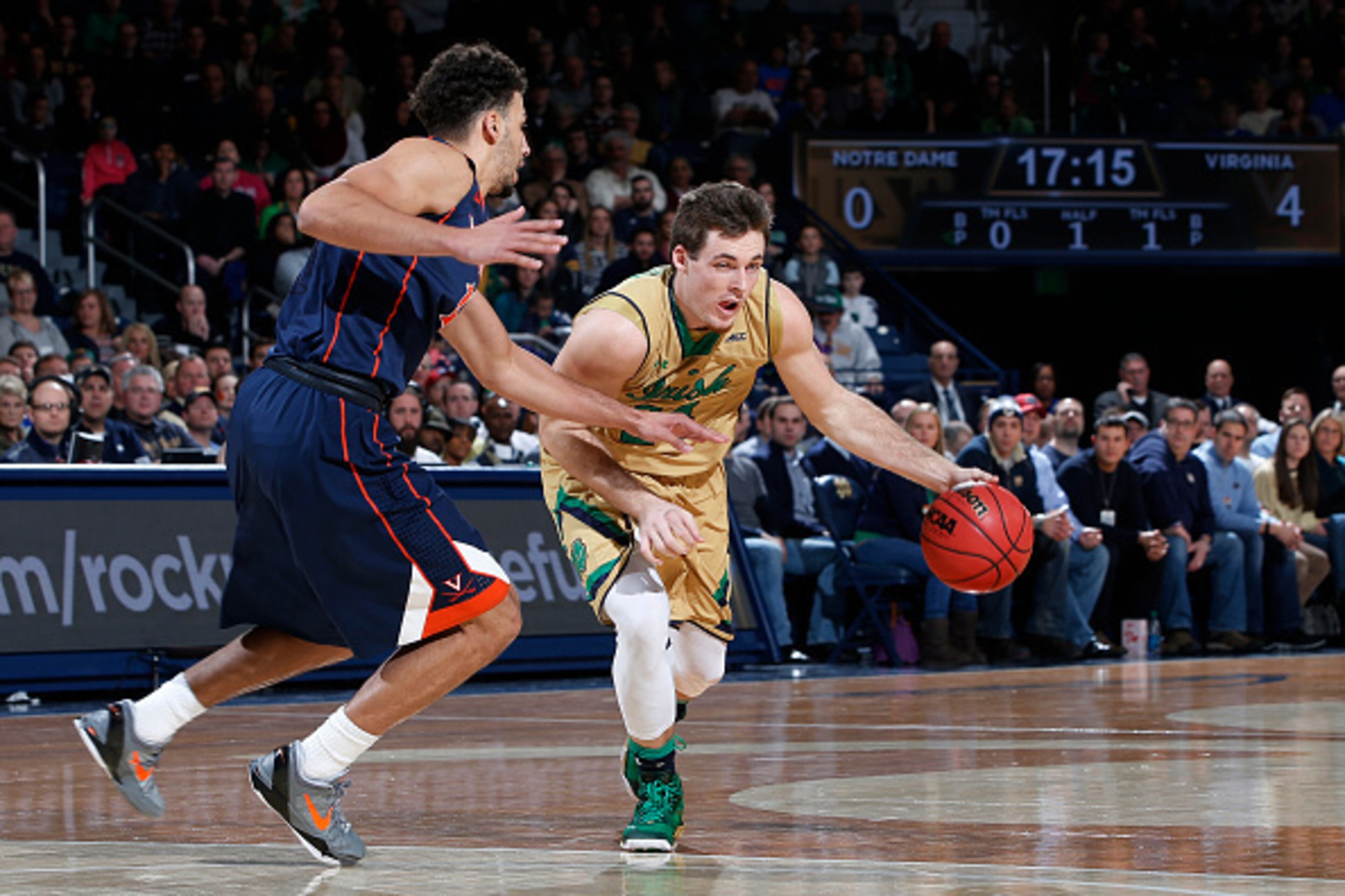 SOUTH BEND, IN - JANUARY 10: Pat Connaughton #24 of the Notre Dame Fighting Irish handles the ball against Anthony Gill #13 of the Virginia Cavaliers in the first half of the game at Purcell Pavilion on January 10, 2015 in South Bend, Indiana. (Photo by J