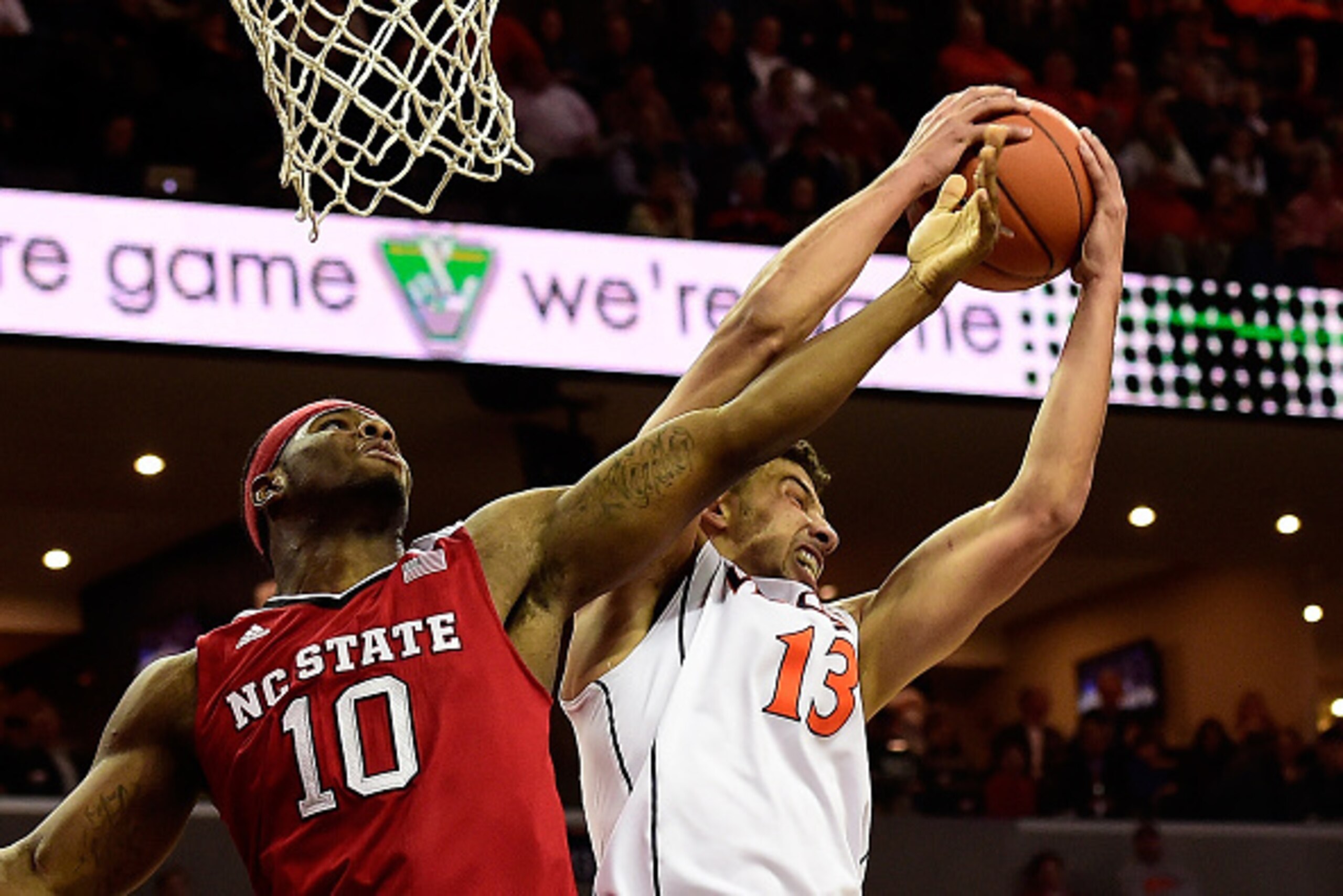 CHARLOTTESVILLE, VA - JANUARY 07: Anthony Gill #13 of the Virginia Cavaliers and Lennard Freeman #10 of the North Carolina State Wolfpack battle for a rebound in the first half during a game at John Paul Jones Arena on January 7, 2015 in Charlottesville, 