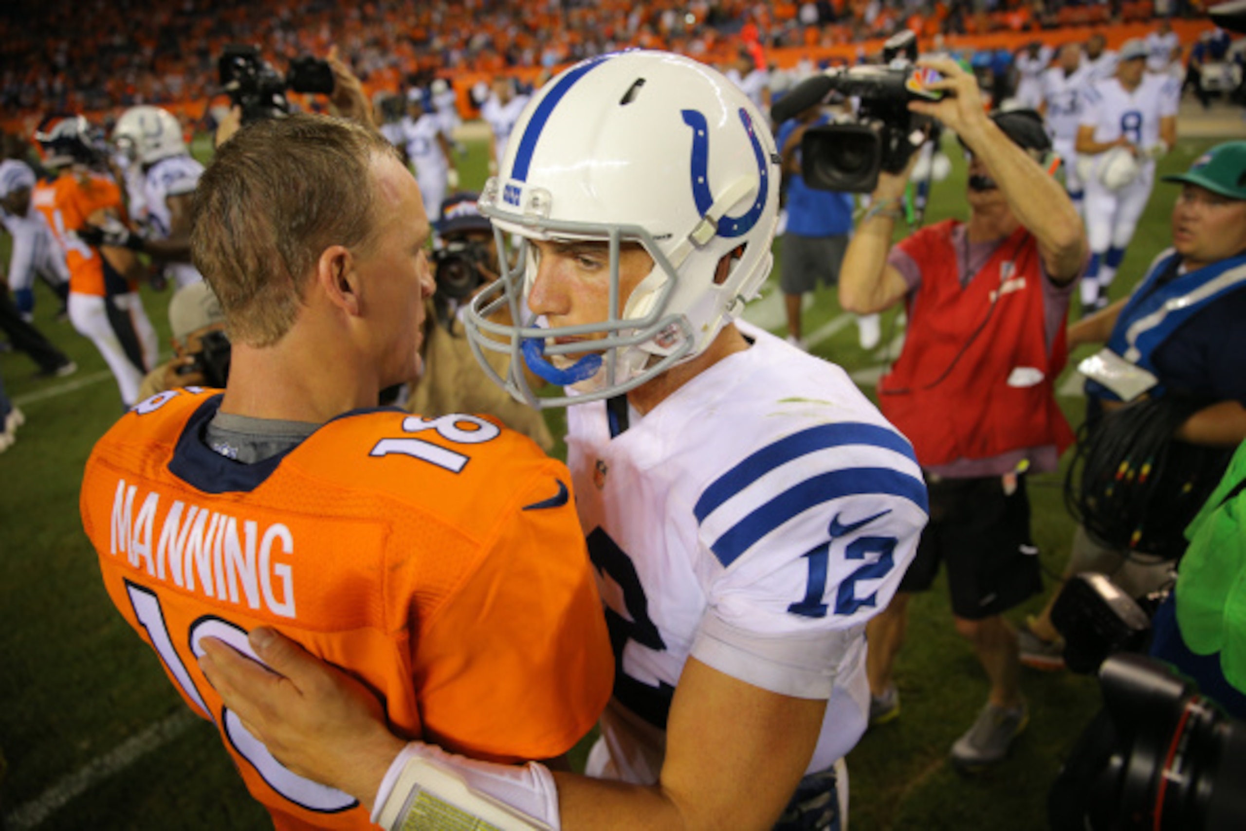 DENVER, CO - SEPTEMBER 7:  Quarterback Peyton Manning #18 of the Denver Broncos and quarterback Andrew Luck #12 of the Indianapolis Colts meet on the field after a game at Sports Authority Field at Mile High on September 7, 2014 in Denver, Colorado.  (Pho