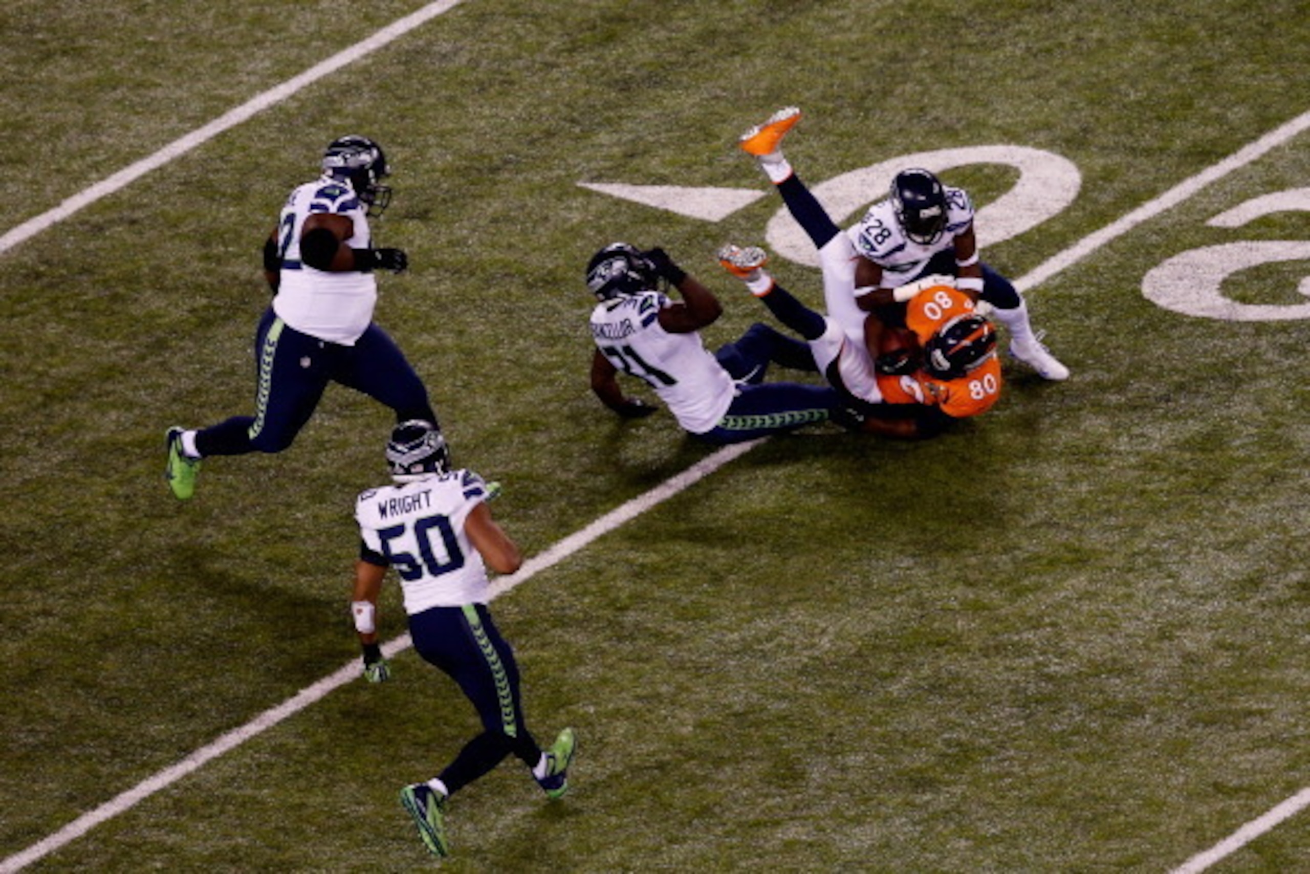 EAST RUTHERFORD, NJ - FEBRUARY 02:  Strong safety Kam Chancellor #31 and cornerback Walter Thurmond #28 of the Seattle Seahawks tackle tight end Julius Thomas #80 of the Denver Broncos during Super Bowl XLVIII at MetLife Stadium on February 2, 2014 in Eas
