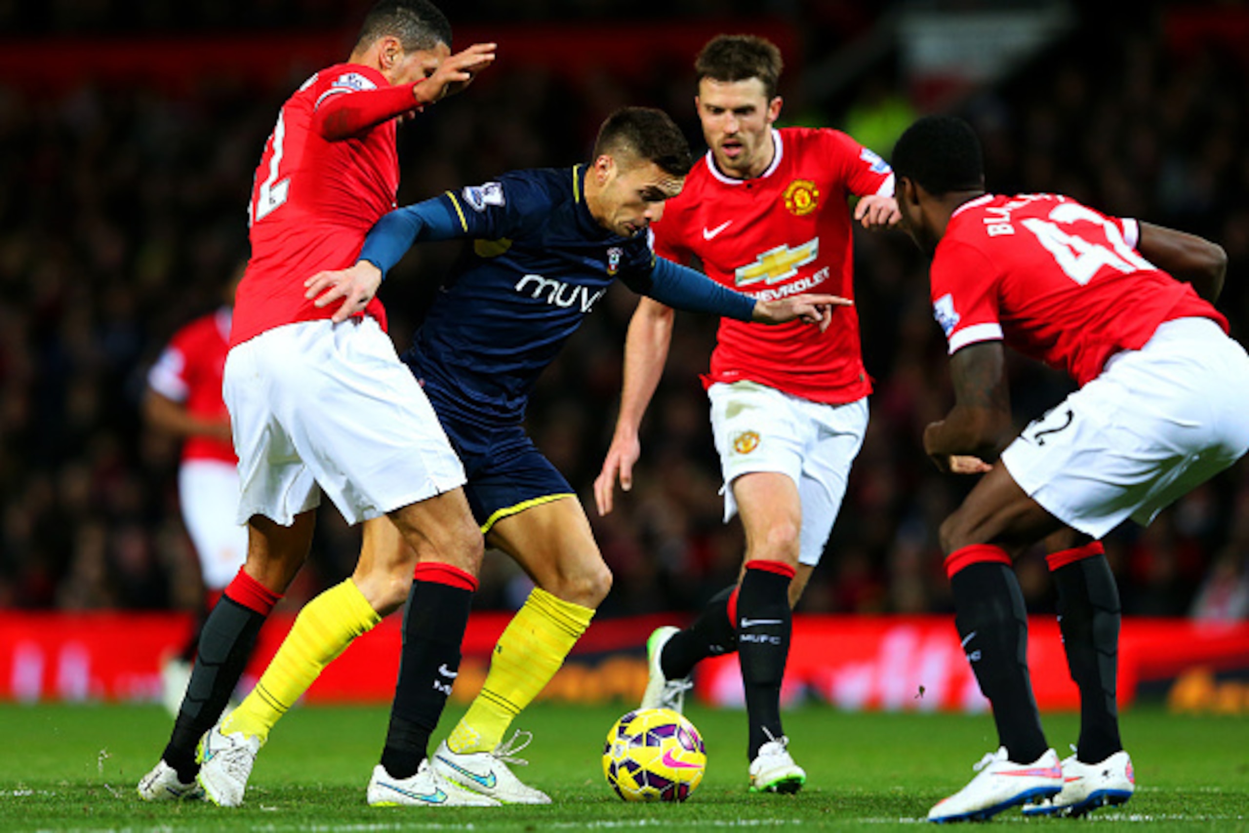 MANCHESTER, ENGLAND - JANUARY 11:  Dusan Tadic of Southampton battles for the ball with Chris Smalling, Michael Carrick and Tyler Blackett of Manchester United during the Barclays Premier League match between Manchester United and Southampton at Old Traff