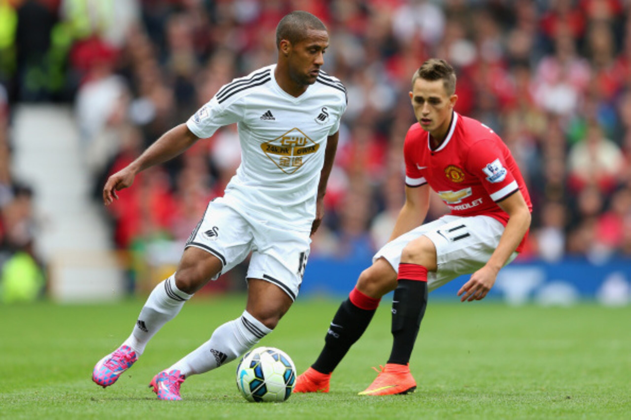 MANCHESTER, ENGLAND - AUGUST 16:  Wayne Routledge of Swansea City competes with Adnan Januzaj of Manchester United during the Barclays Premier League match between Manchester United and Swansea City at Old Trafford on August 16, 2014 in Manchester, Englan