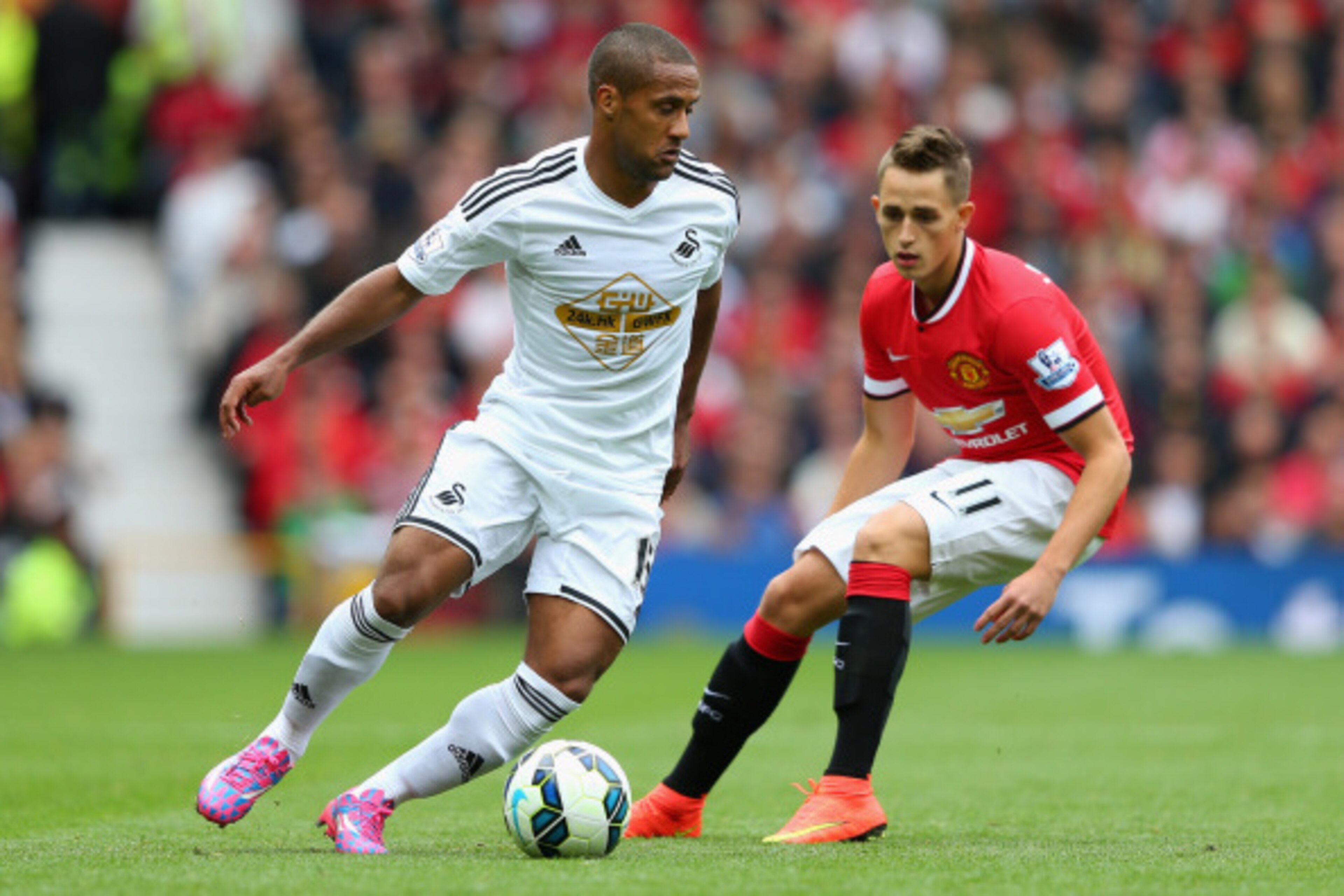 MANCHESTER, ENGLAND - AUGUST 16:  Wayne Routledge of Swansea City competes with Adnan Januzaj of Manchester United during the Barclays Premier League match between Manchester United and Swansea City at Old Trafford on August 16, 2014 in Manchester, Englan