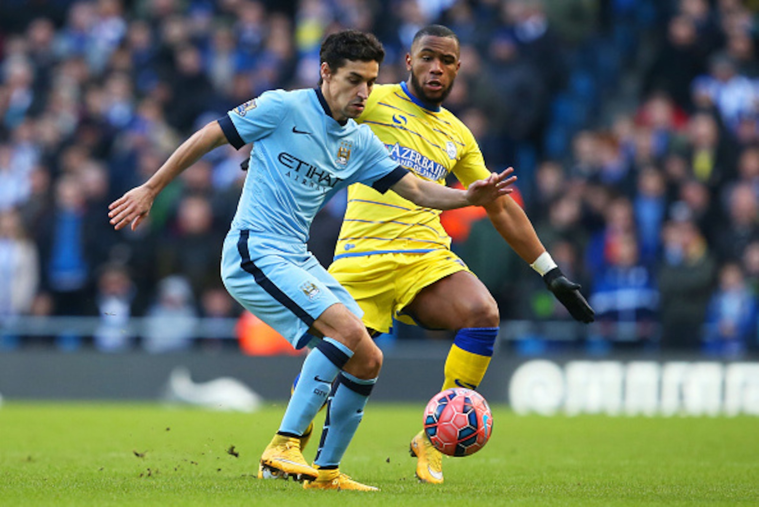 MANCHESTER, ENGLAND - JANUARY 04:  Jesus Navas of Manchester City is closed down by Claude Dielna of Sheffield Wednesday during the FA Cup Third Round match between  Manchester City and Sheffield Wednesday at Etihad Stadium on January 4, 2015 in Mancheste