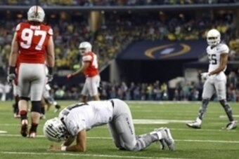 Jan 12, 2015; Arlington, TX, USA; Oregon Ducks quarterback Marcus Mariota (8) tries to get up in the fourth quarter as Ohio State Buckeyes defensive lineman Joey Bosa (97) walks away from the play in the 2015 CFP National Championship Game at AT&T Stadium