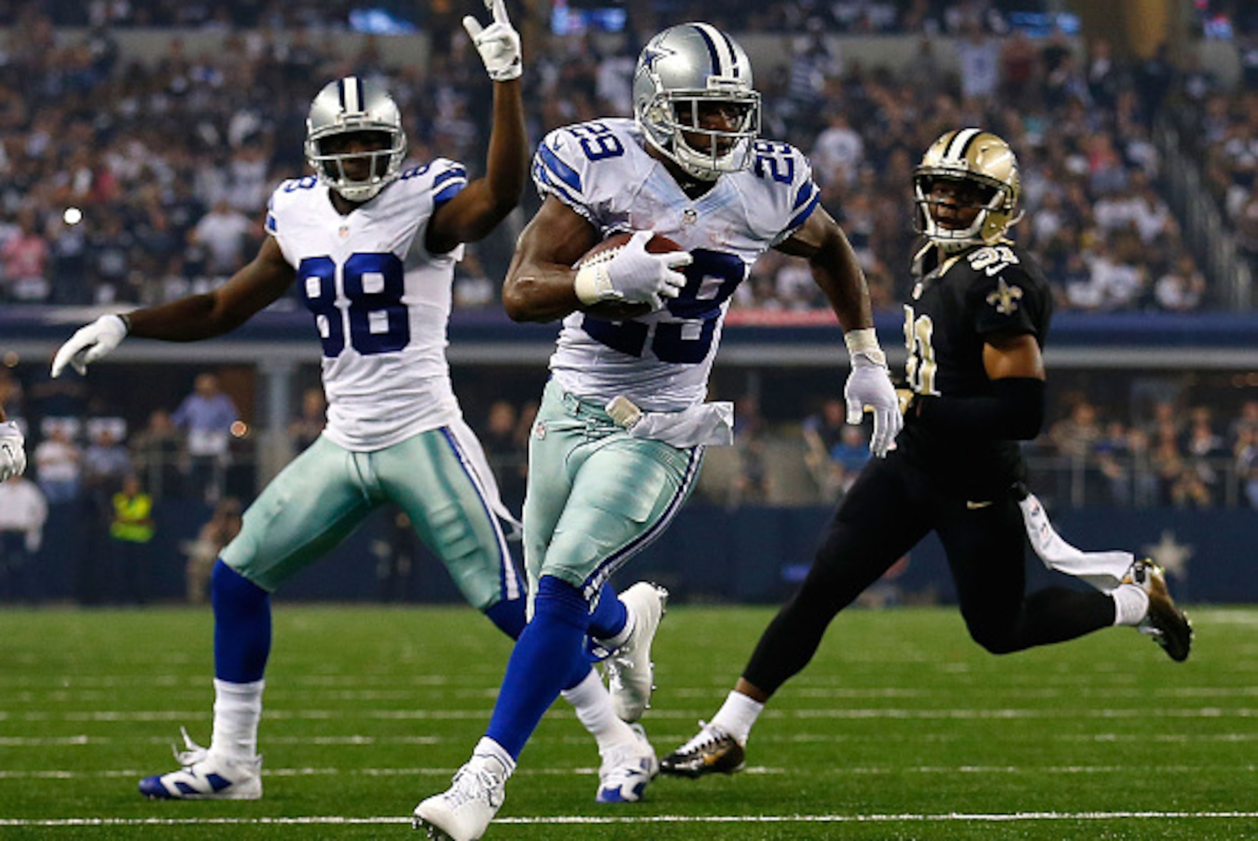 ARLINGTON, TX - SEPTEMBER 28:  DeMarco Murray #29 of the Dallas Cowboys runs for a touchdown as Dez Bryant #88 of the Dallas Cowboys reacts and Jairus Byrd #31 of the New Orleans Saints watches in the first half at AT&T Stadium on September 28, 2014 in Ar