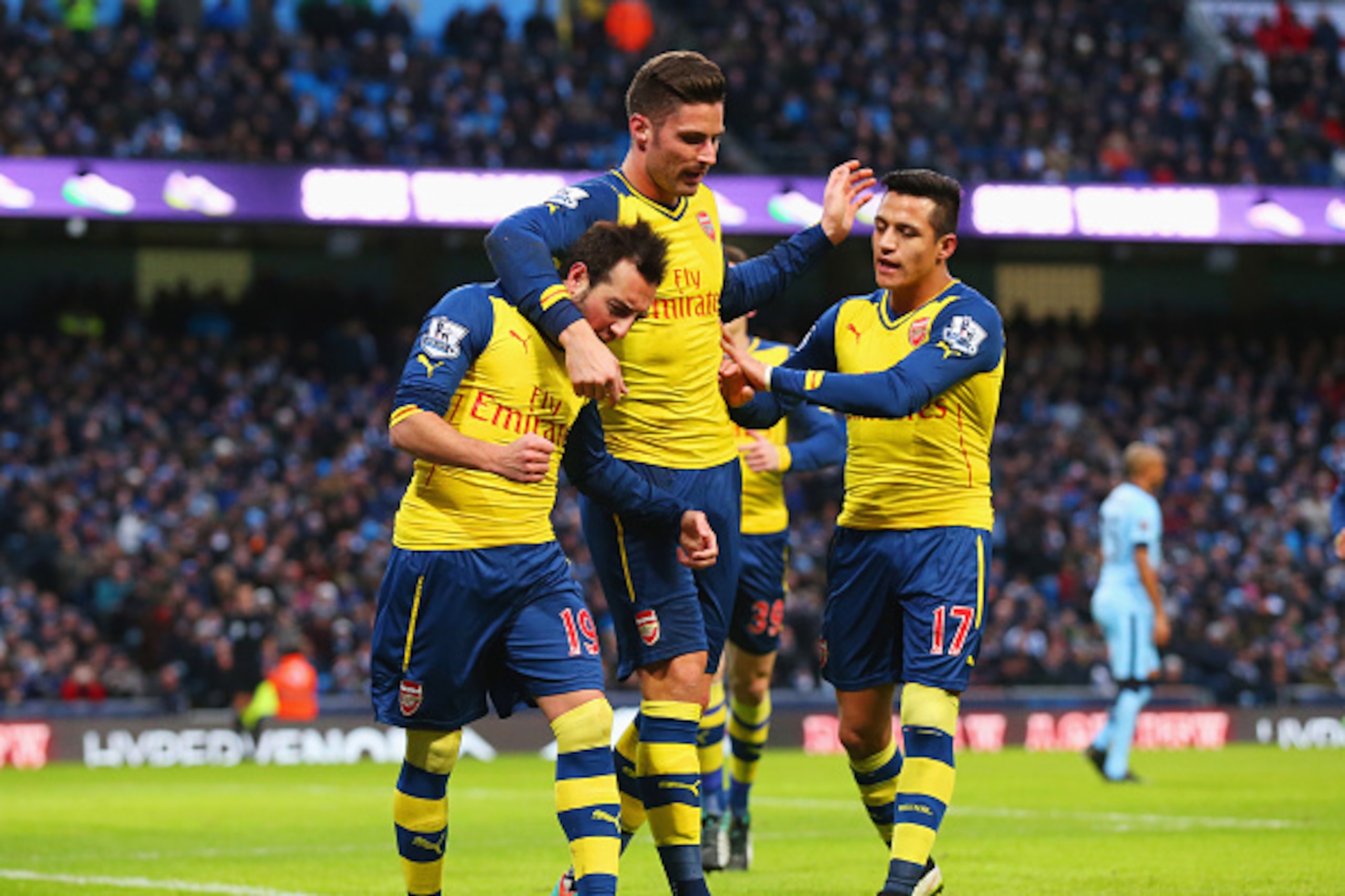 MANCHESTER, ENGLAND - JANUARY 18:  Santi Cazorla of Arsenal (L) celebrates with Olivier Giroud (C) and Alexis Sanchez as he scores their first goal from a penalty during the Barclays Premier League match between Manchester City and Arsenal at Etihad Stadi